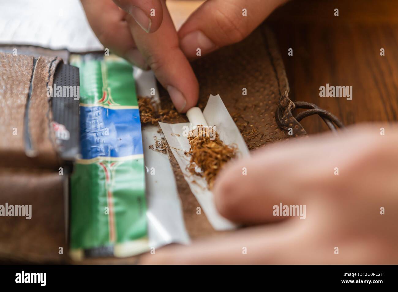una persona rotola una sigaretta con tabacco Foto Stock