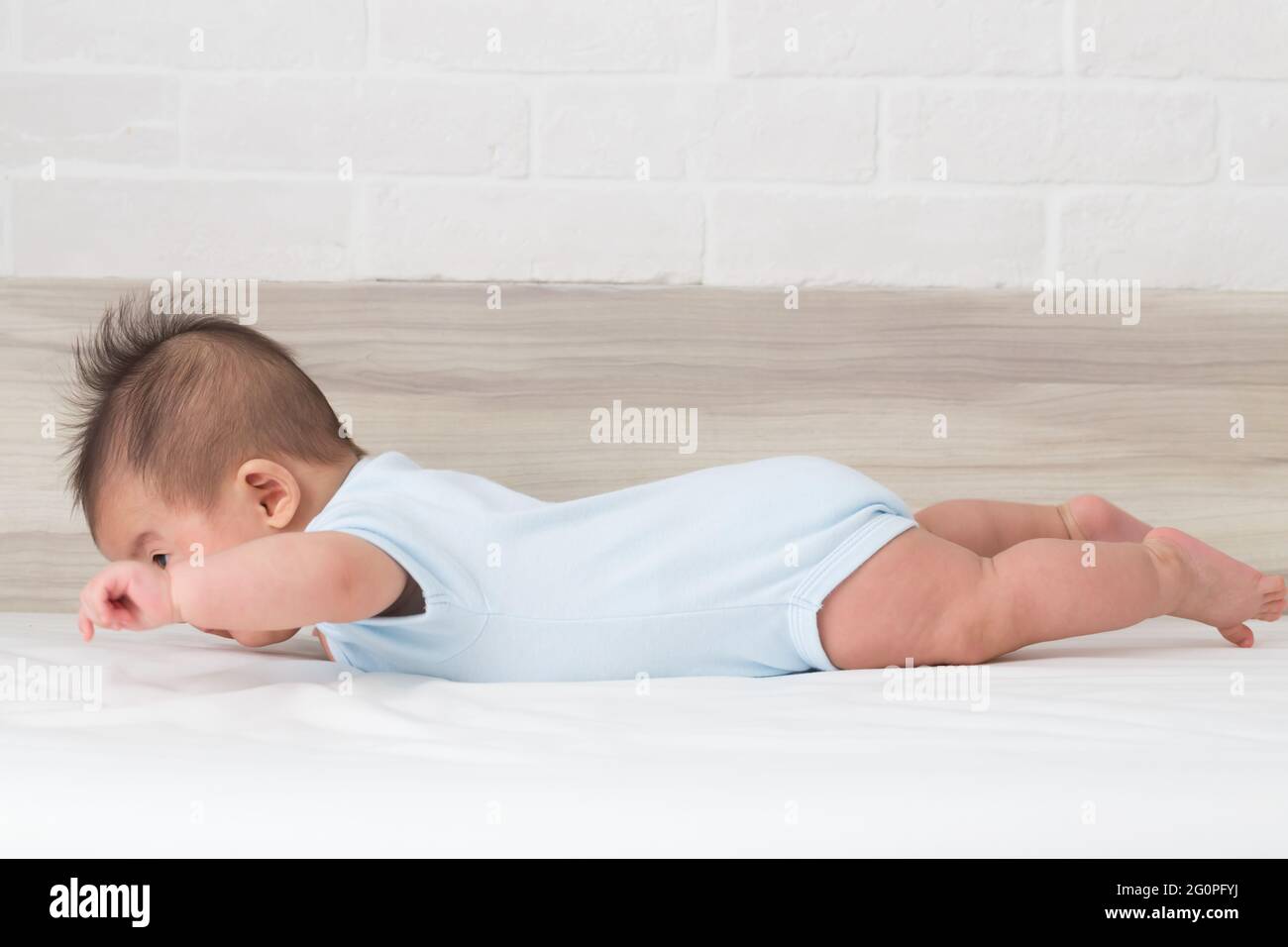 Il bambino solleva il petto e a volte le gambe con le braccia sollevate lateralmente, concetto di azione delle abilità del bambino e del bambino Foto Stock