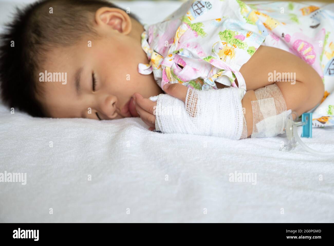 Asian bimbo che dorme sul letto con set per infusione al bambino dipartimento dell'ospedale. I bambini con malattie infettive IPD, pneumococciche invasive Dis Foto Stock