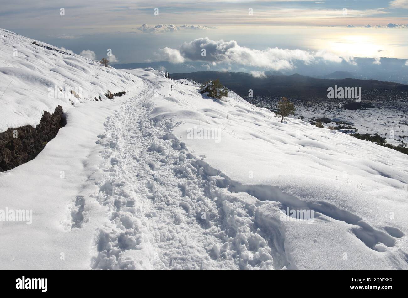 Sentieri escursionistici sul sentiero di alta montagna coperto di neve in Sicilia all'orizzonte basse nuvole nel Parco dell'Etna Foto Stock