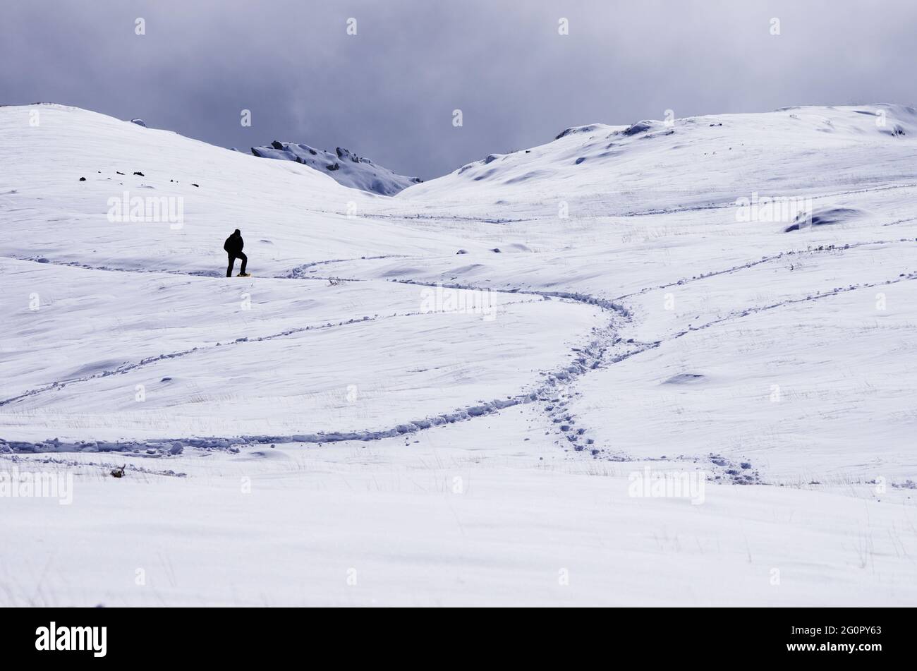 Un escursionista che cammina attraverso il campo di neve in Sicilia un percorso di alta montagna per avvicinare la cima dell'Etna punto di riferimento della natura e del turismo all'aperto Foto Stock
