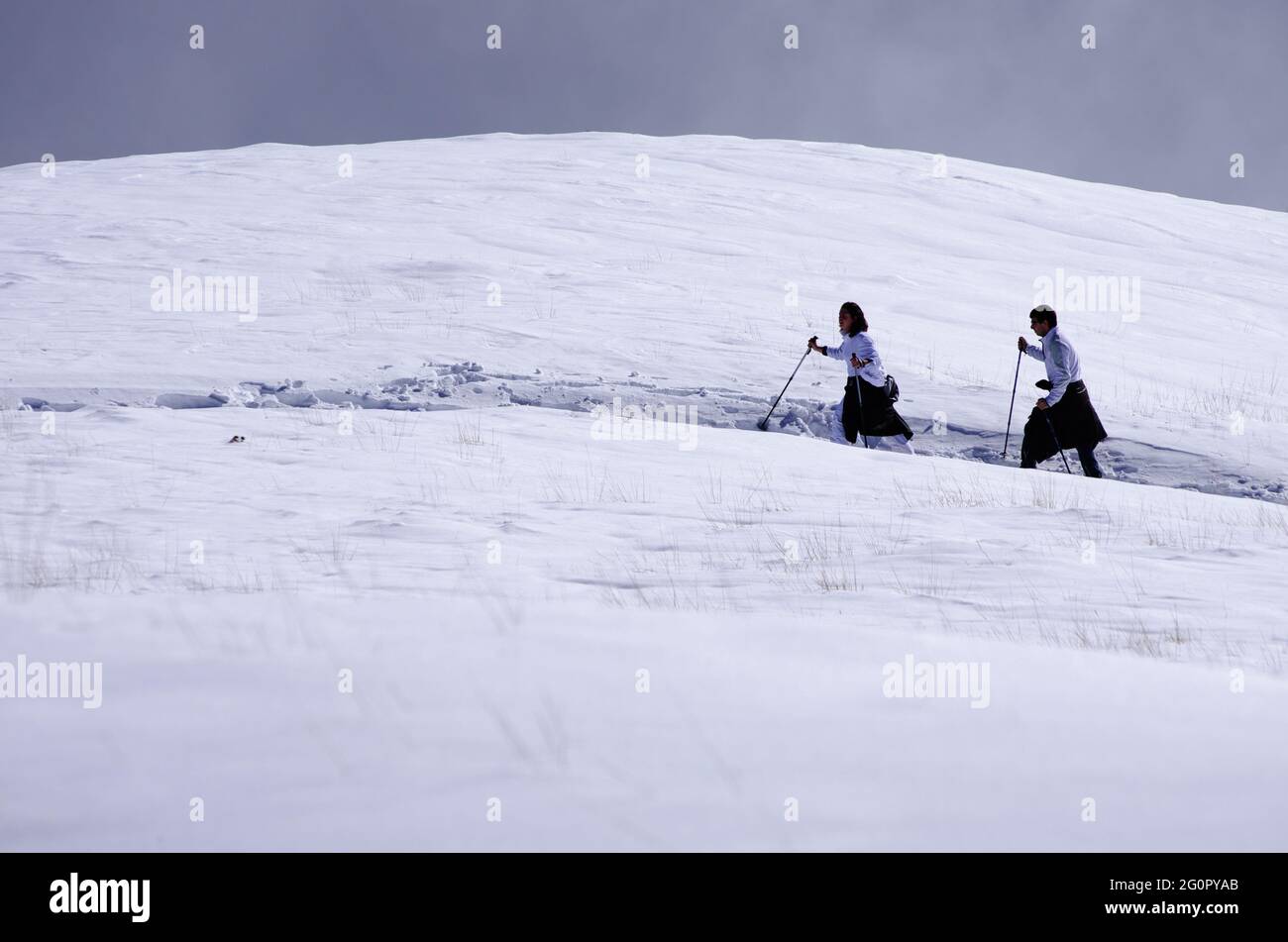 Due escursionisti che camminano attraverso il campo di neve in Sicilia un sentiero di alta montagna per avvicinare la cima dell'Etna punto di riferimento della natura e del turismo all'aperto Foto Stock