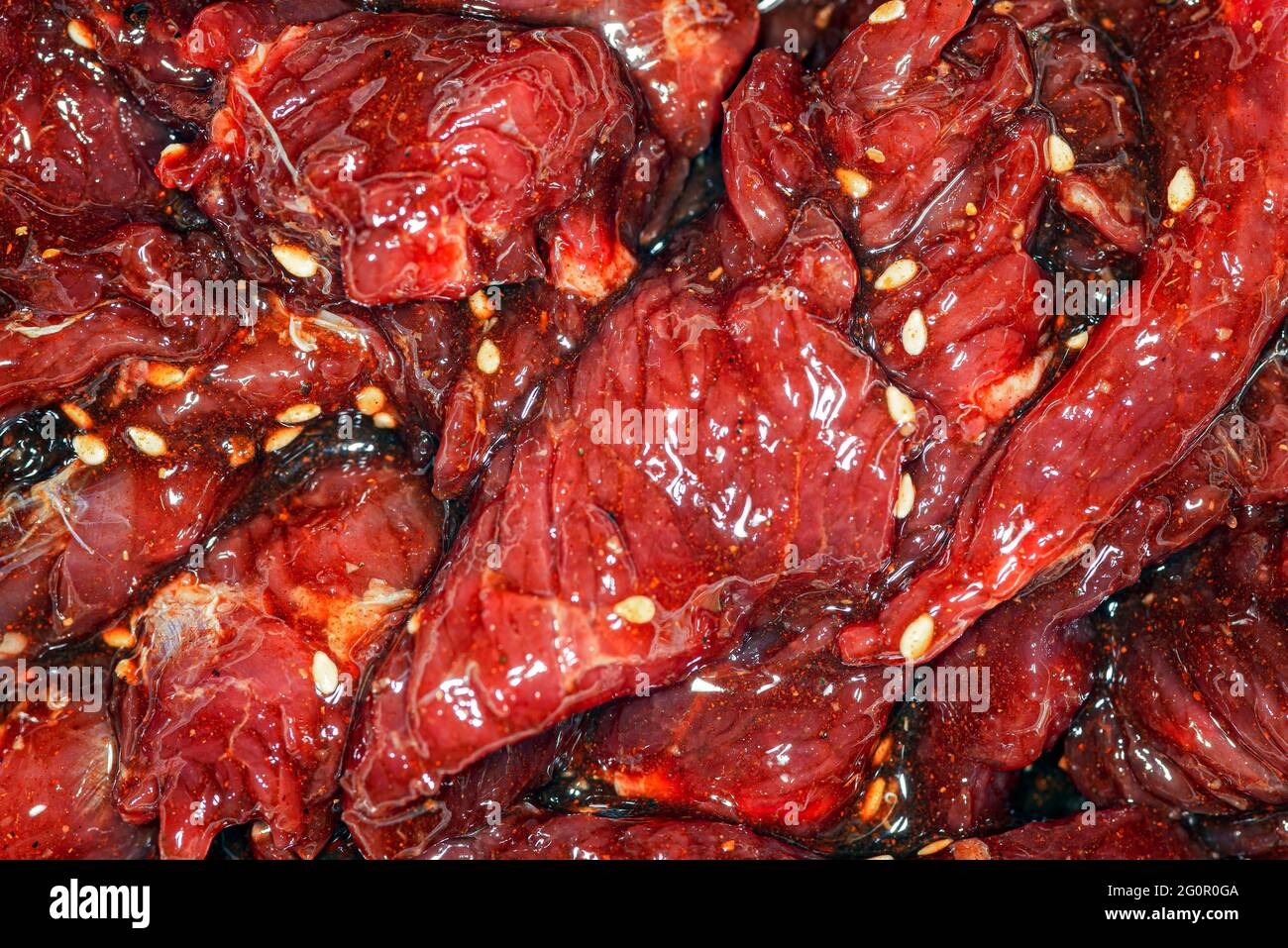 Fette di manzo marinate, luminose e succose, con spezie, olio e semi di sesamo Foto Stock