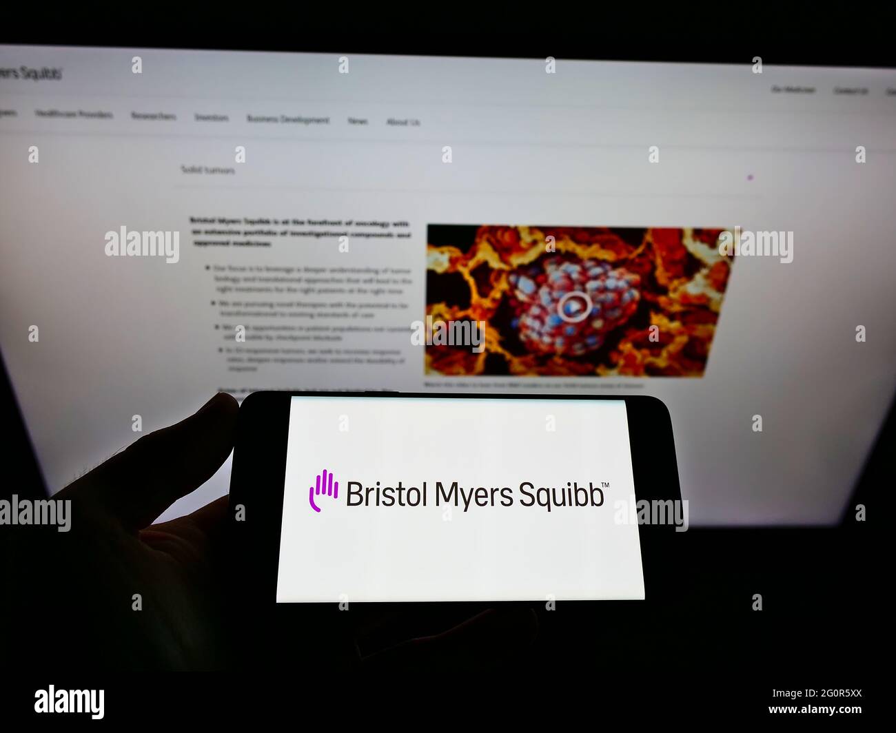 Persona che tiene il telefono mobile con il logo della società farmaceutica statunitense Bristol Myers Squibb (BMS) sullo schermo davanti alla pagina web. Mettere a fuoco il display del telefono. Foto Stock