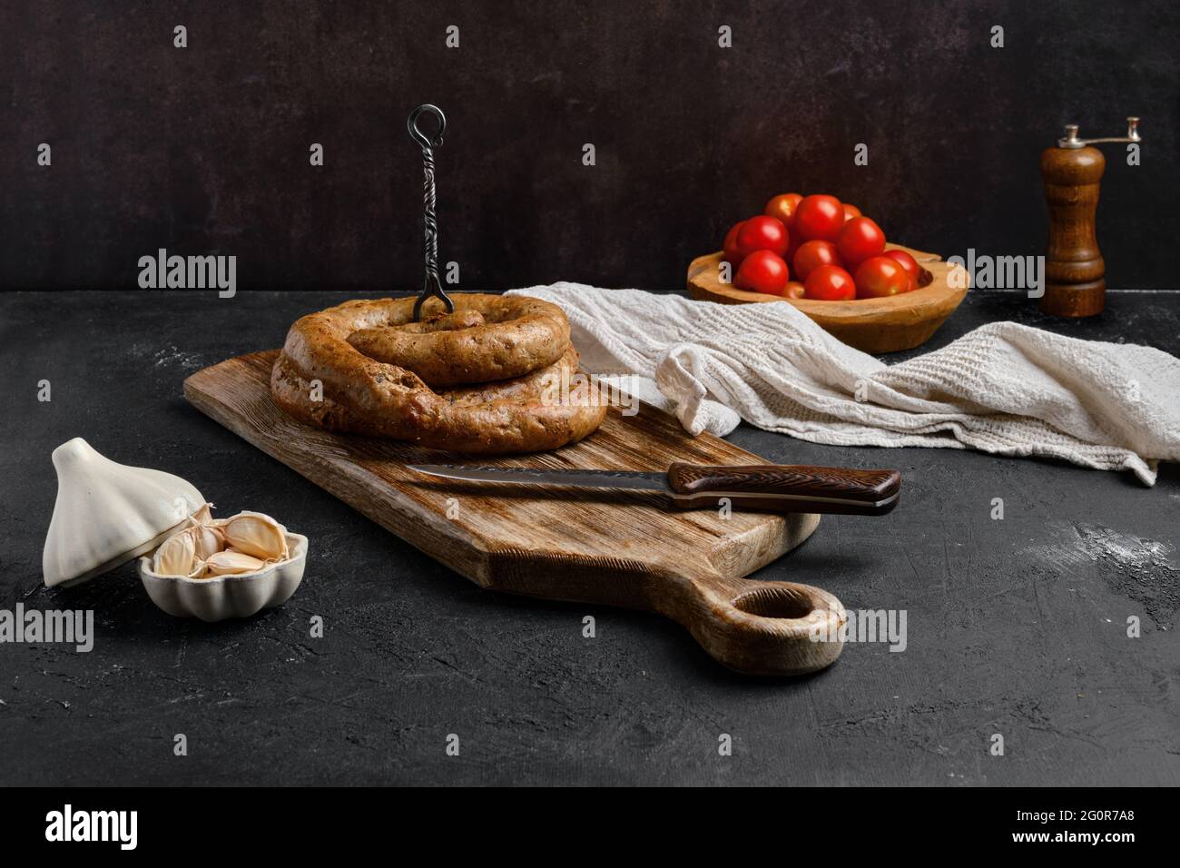 Salsiccia di carne di cavallo con aglio arrotolato su tagliere di legno Foto Stock