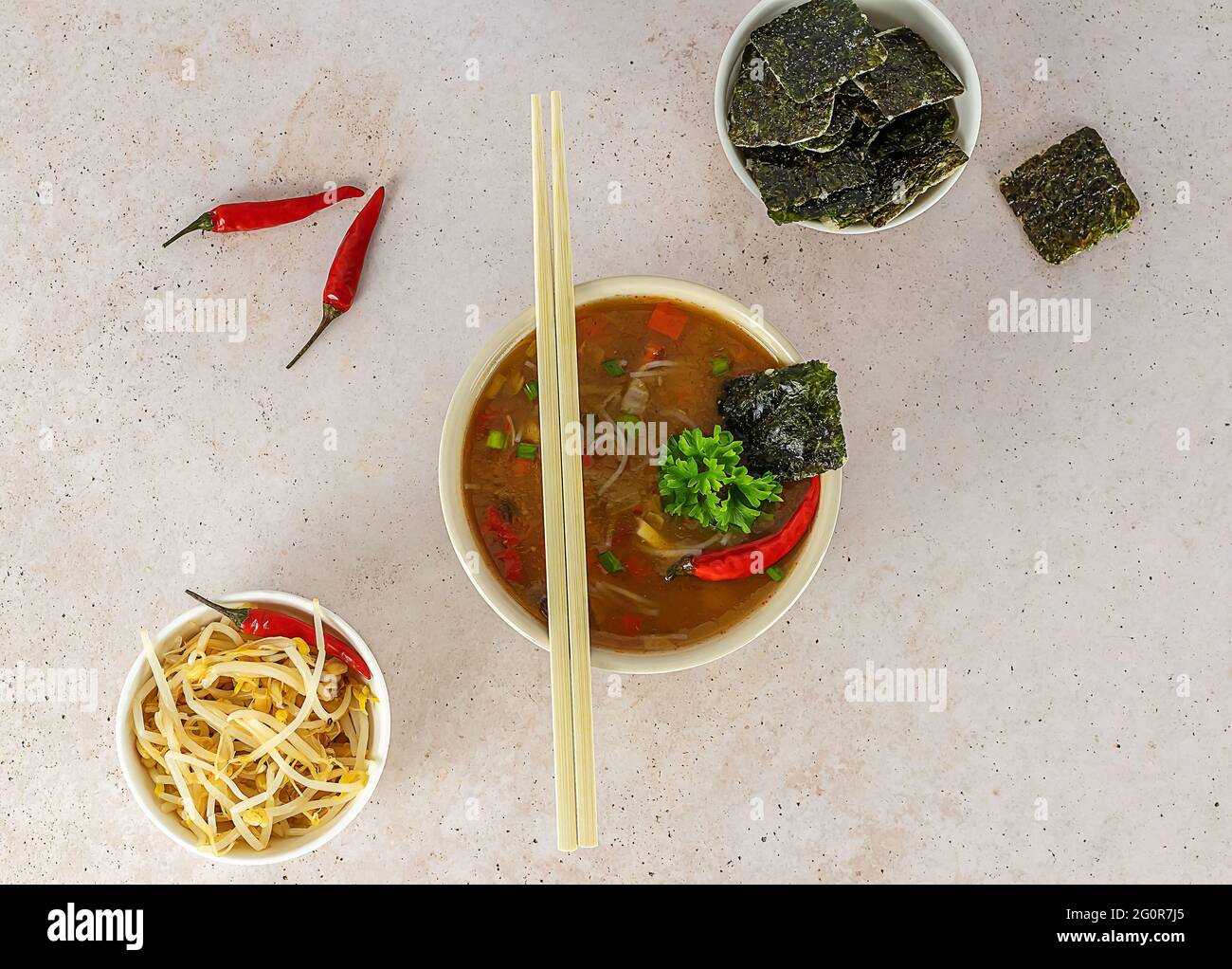 Zuppa asiatica di noodle piccante con alghe e germogli di fagioli. Servita in una ciotola con bastoncini. Vista dall'alto. Foto Stock