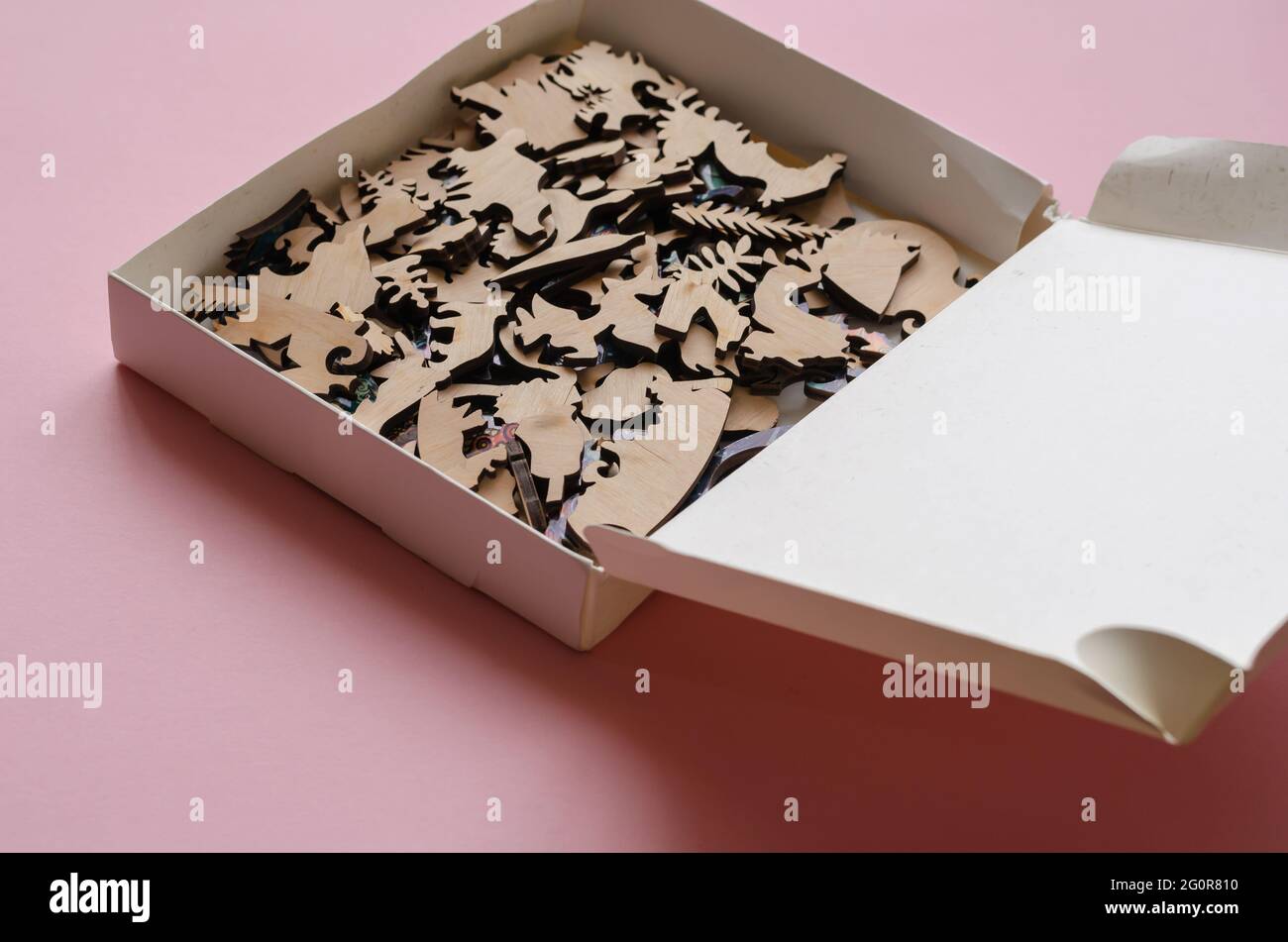 Open-box con un puzzle di legno su sfondo rosa. Un puzzle complesso di forme e articolazioni estremamente precise. Tempo libero attivo. Giochi di logica. Foto Stock