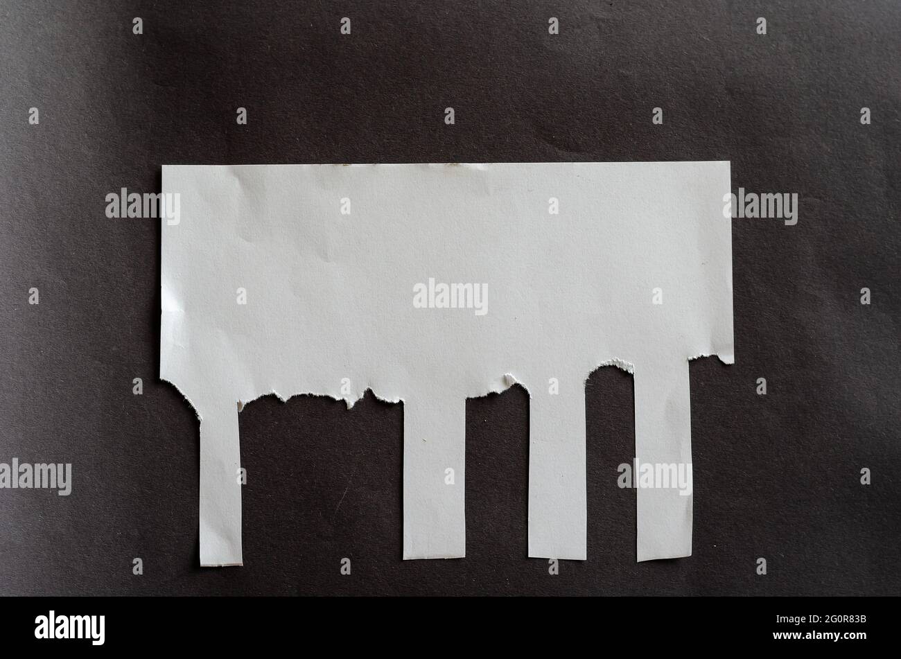 Foglio bianco vuoto con linguette a strappo su sfondo grigio. Foglio di carta sgualcito con strisce irregolari. Non tutti i segnalibri a strappo. Via A. Foto Stock