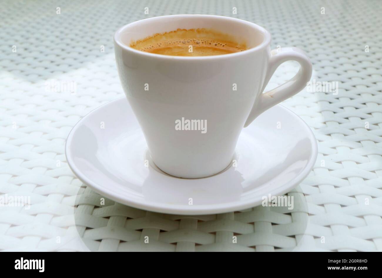 Preparare una tazza di caffè caldo e schiumoso isolato su un tavolo bianco Foto Stock