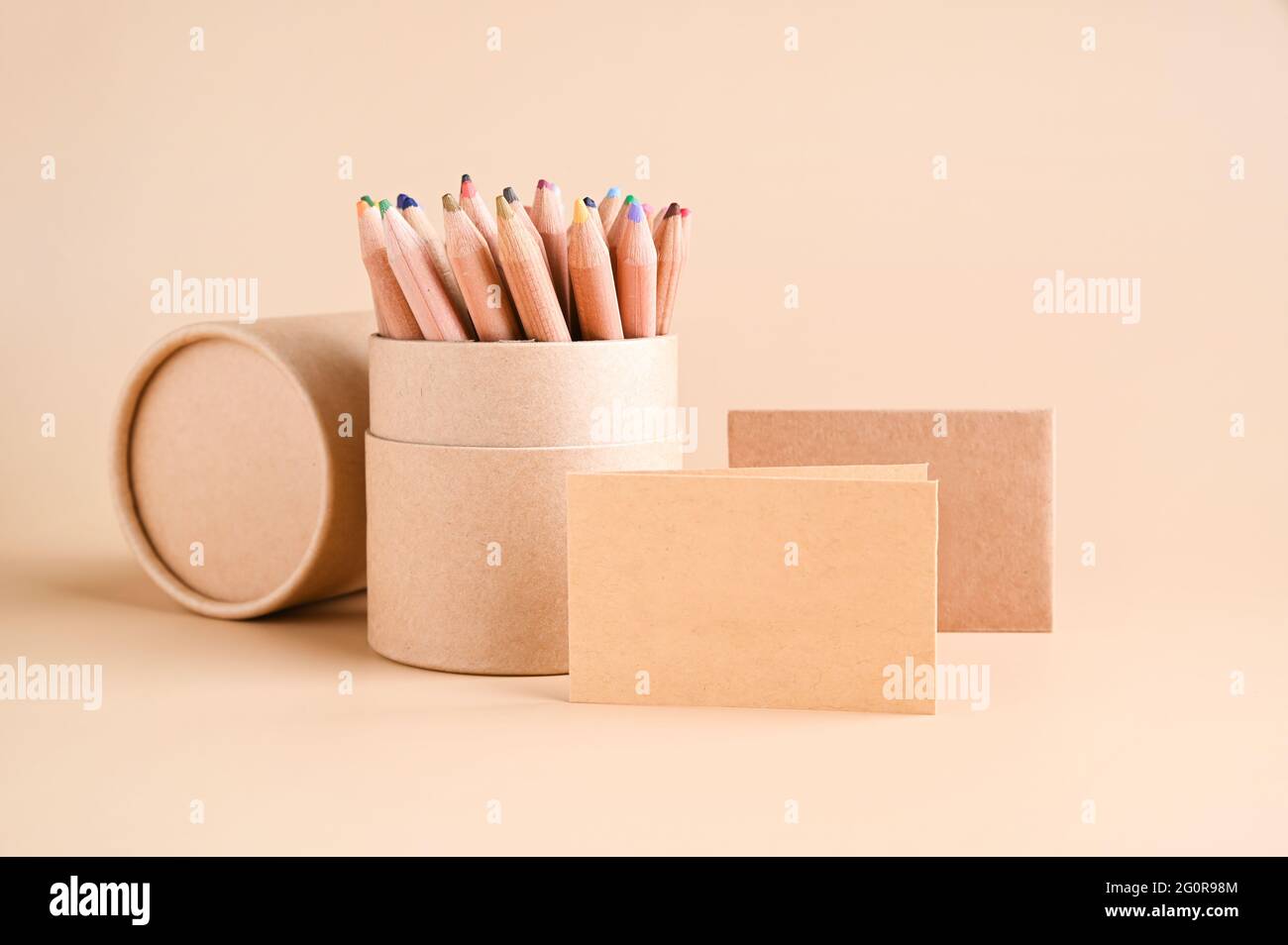 Mockup di biglietti da visita, carta eco-kraft e una serie di matite colorate su sfondo beige. Concetto di cancelleria eco-compatibile. Riciclabile. Foto di alta qualità. Foto Stock