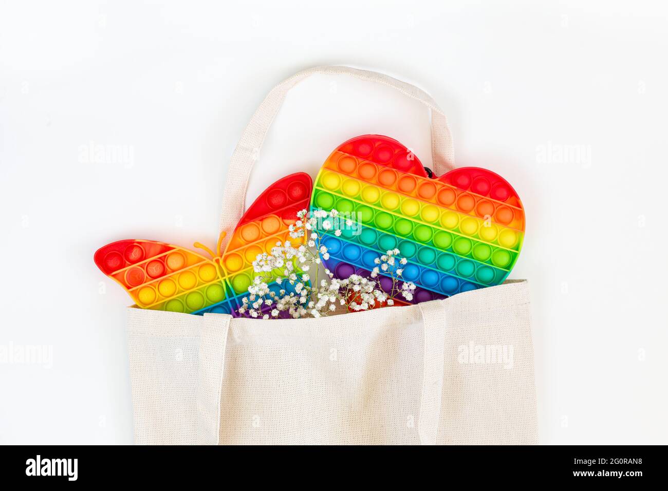 Giocattoli Pop it, semplice colore arcobaleno Dimple in una borsa per la spesa su uno sfondo bianco Foto Stock