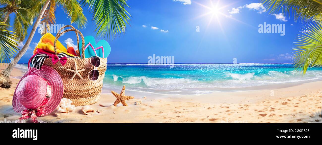 Borsa da spiaggia su sabbia tropicale con palme e mare soleggiato Foto Stock