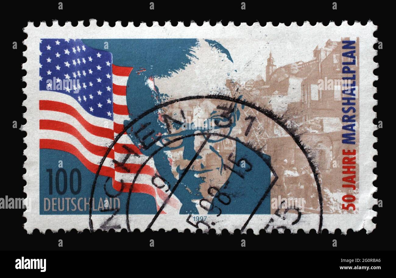Un francobollo stampato in Germania mostra la bandiera degli Stati Uniti, George Marshall e sito bomba, 50 ° anniversario del piano Marshall, circa 1997 Foto Stock