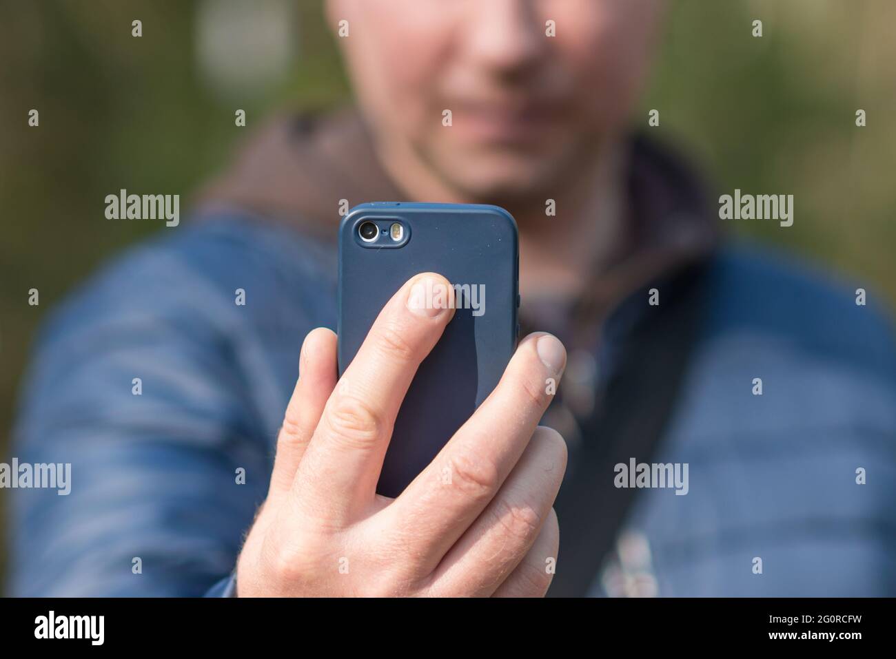 Un uomo con il suo smartphone cellulare alla ricerca del segnale di ricezione nella foresta primaverile.close up. Foto Stock