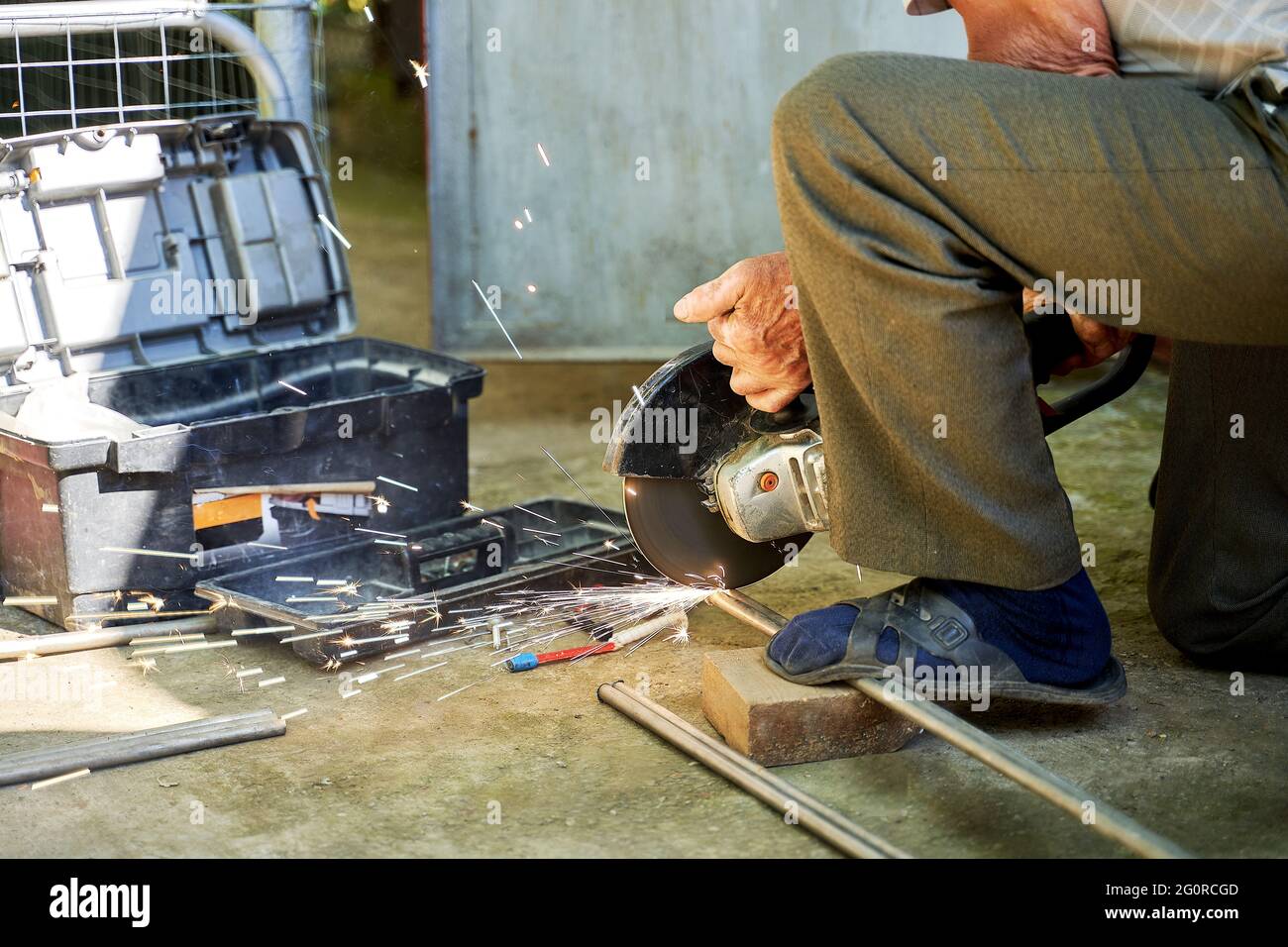 un uomo taglia un tubo di titanio con una smerigliatrice Foto Stock