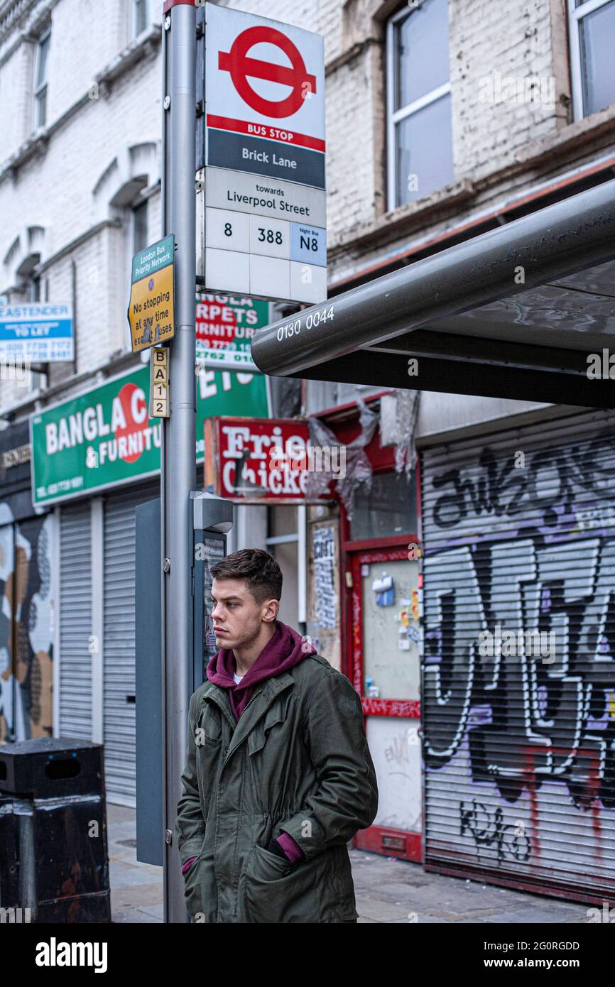 Giovane bell'uomo che aspetta alla fermata dell'autobus a Londra . Foto Stock