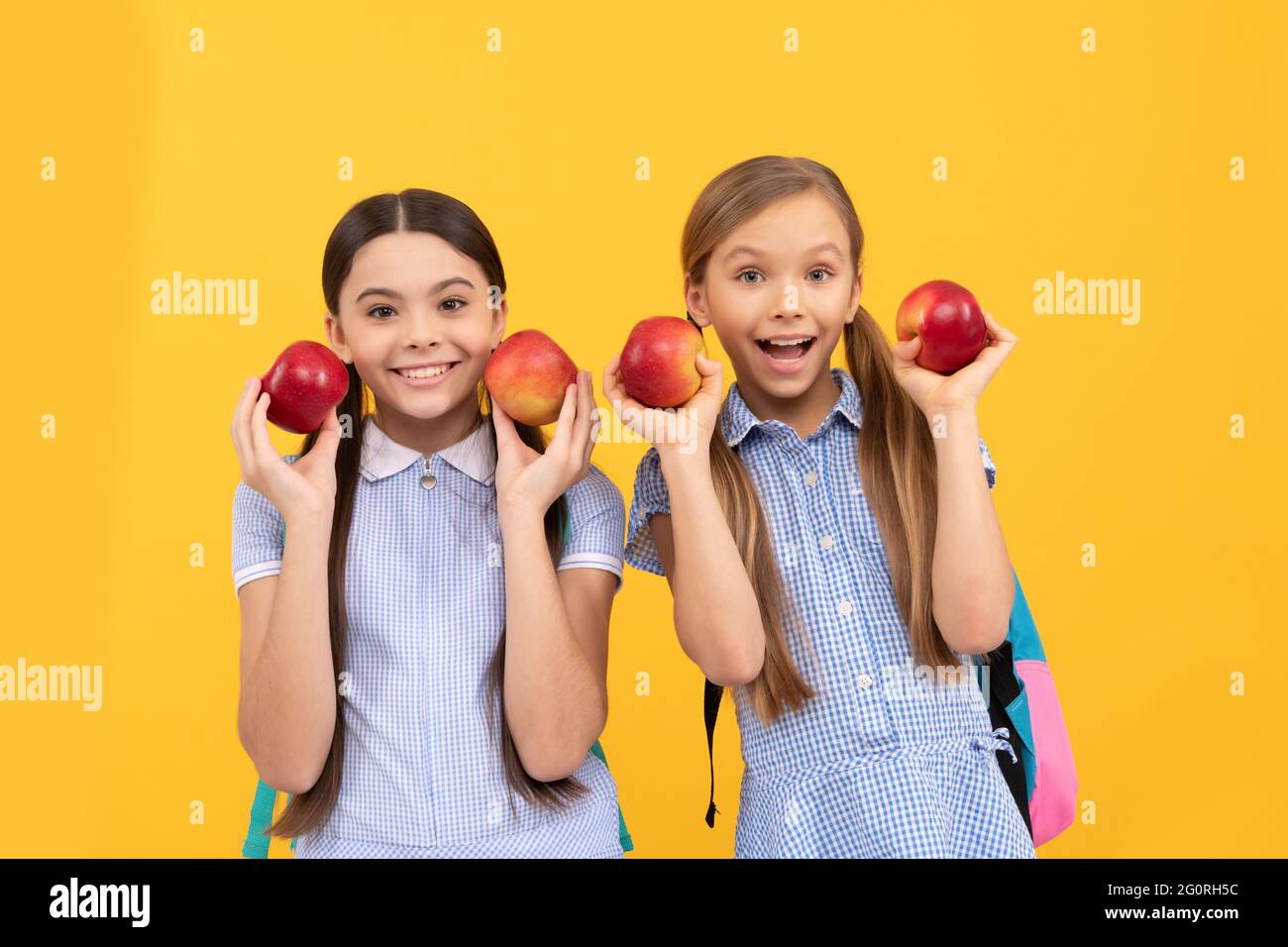Felici i bambini tornano a scuola tenendo le mele per mangiare sano, nutrizione infantile Foto Stock