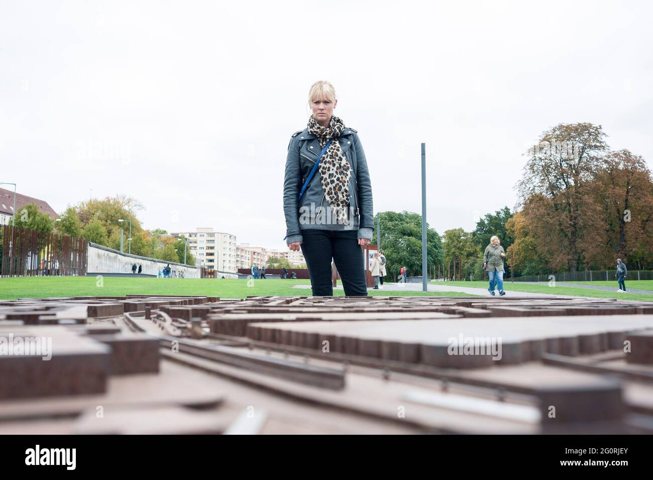Una donna si trova in un parco a Berlino, in Germania, guardando una mappa 3D della zona e vedendo dove il Muro di Berlino ha diviso la città. Foto Stock