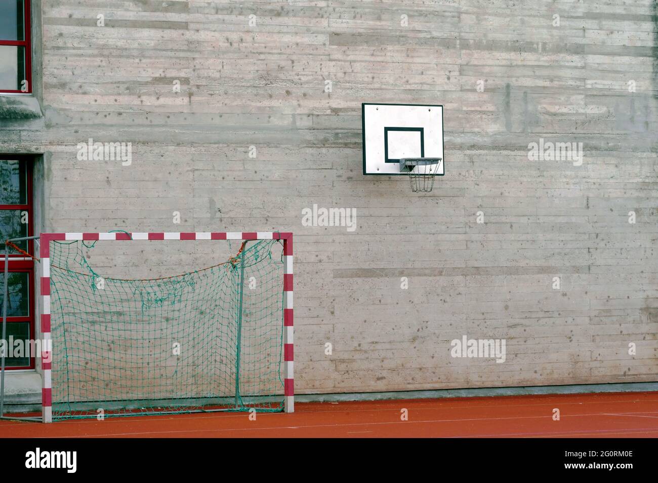 Muro di cemento con un cerchio da basket e pallamano gol sul terreno accanto ad esso. Foto Stock Muro di cemento con un cerchio da basket e pallamano gol sul terreno accanto ad esso. Foto Stock