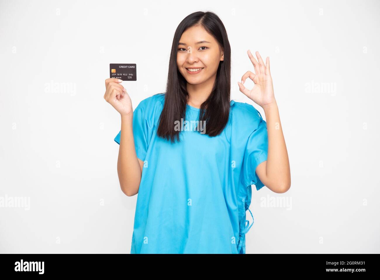 Giovane asiatico bella donna paziente in possesso di carta di credito assicurazione infortuni personale e ok segno isolato su sfondo bianco, PA e Health claim serv Foto Stock