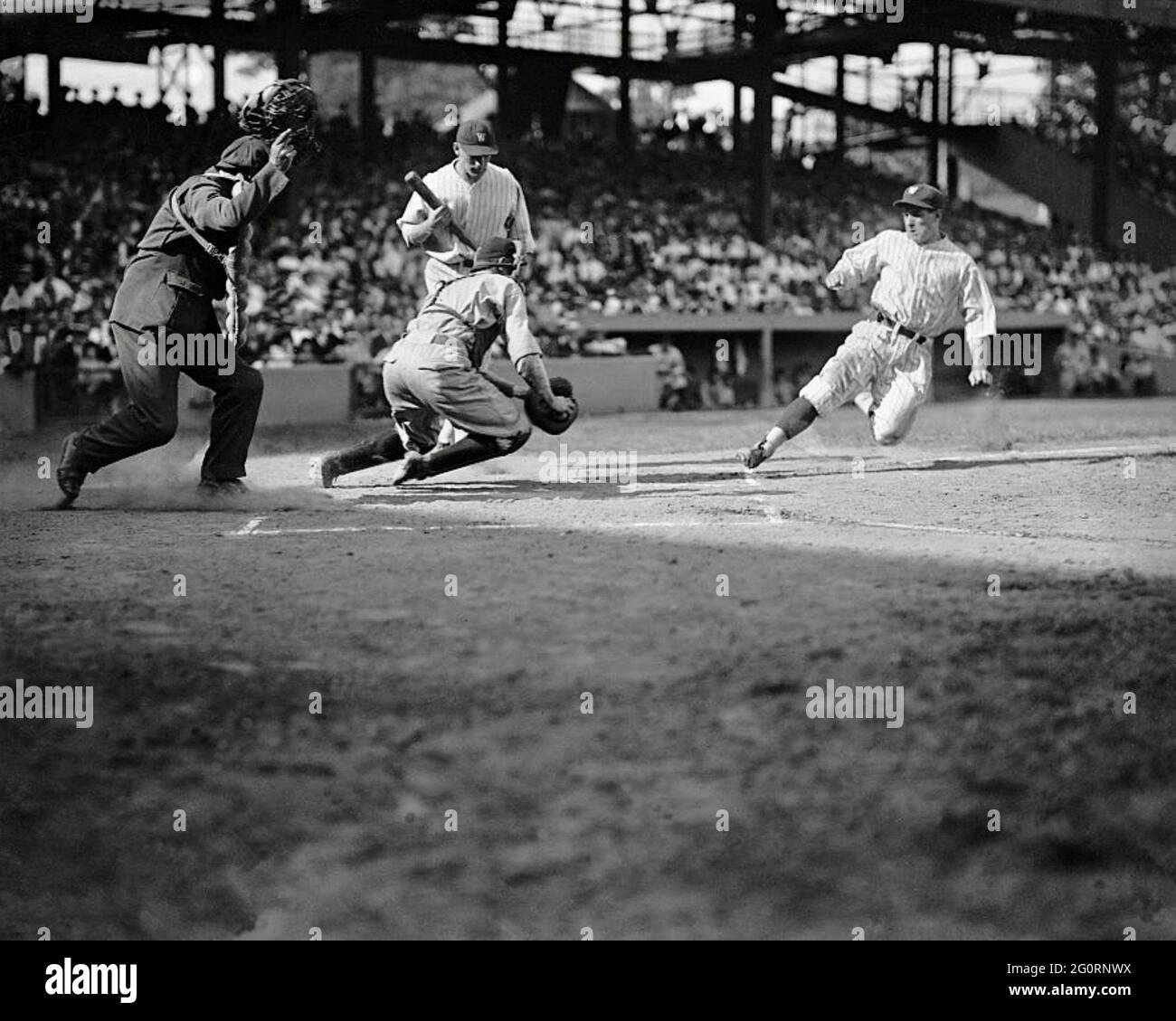 Stanley Harris, Washington sta cercando di rubare a casa come James Sewell, Cleveland catcher si prepara per il tag. Oswald Bluege al pipistrello. 13 agosto 1925. Foto Stock