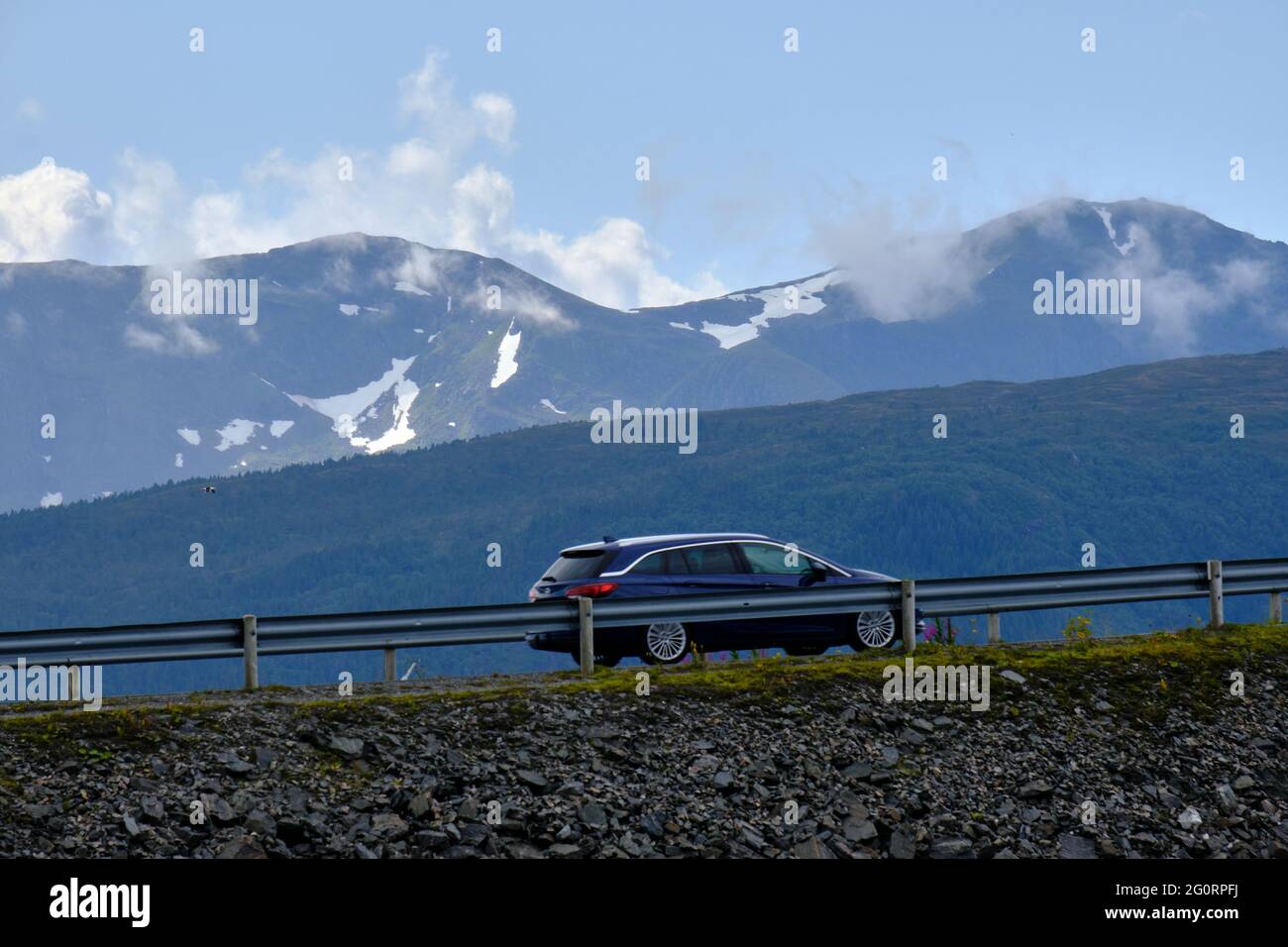 VEVANG, NORVEGIA - 27 luglio 2020: Un'auto turistica è in viaggio tra le montagne innevate, vicino alla strada dell'Oceano Atlantico in Norvegia Foto Stock