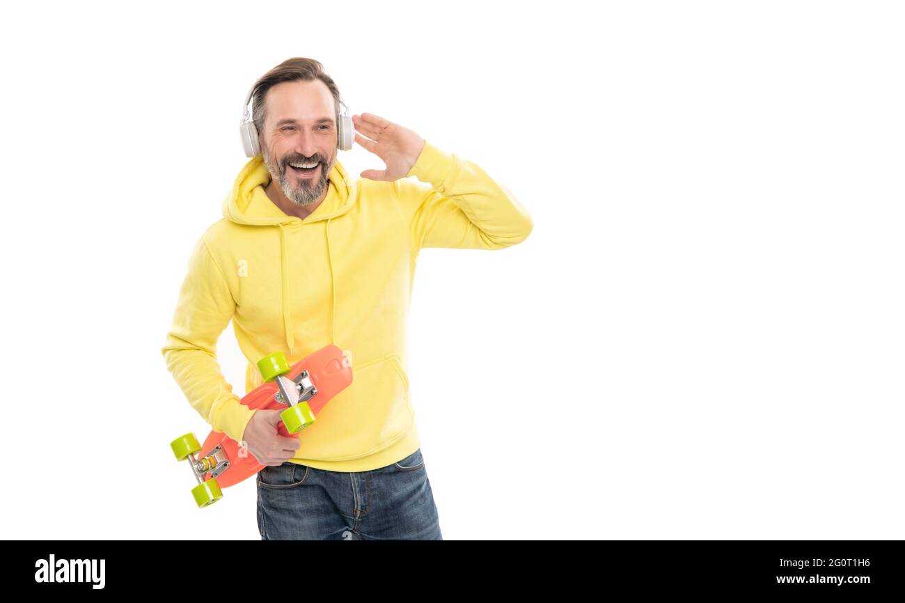 happy uomo maturo skateboarder ascoltare musica indossando cuffie tenere penny skateboard, a tratti. Foto Stock