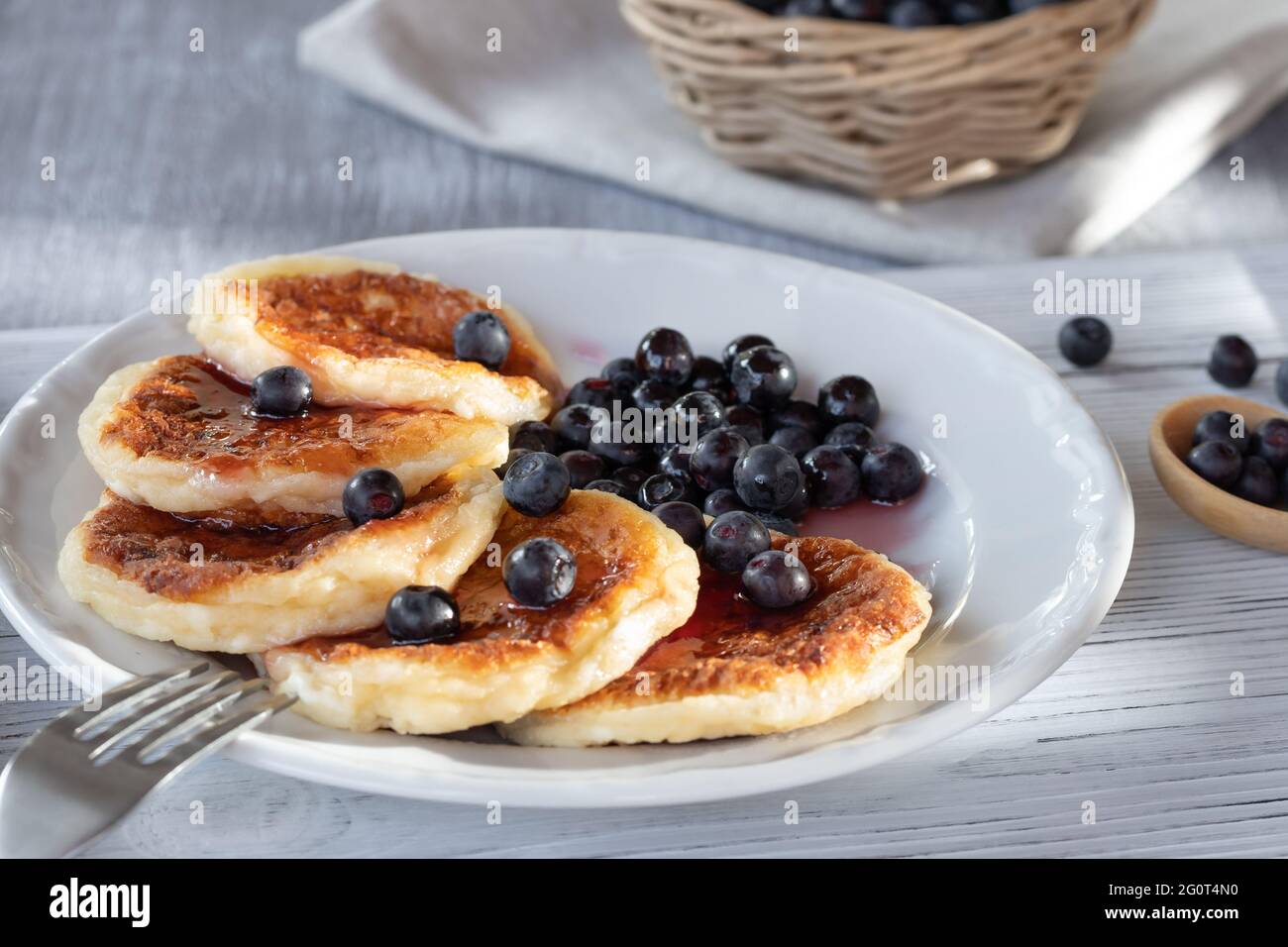Frittelle fresche di cottage con formaggio e mirtilli sciroppati. Colazione estiva nel villaggio. Foto Stock