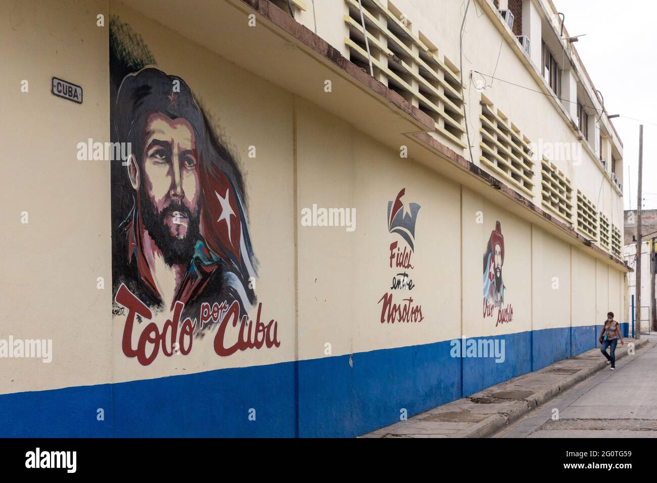Immagini politiche in via Cuba a Santiago de Cuba, Cuba. Un'immagine di che Guevara, una bandiera cubana, e uno slogan sono visti dipinti nel muro. Foto Stock
