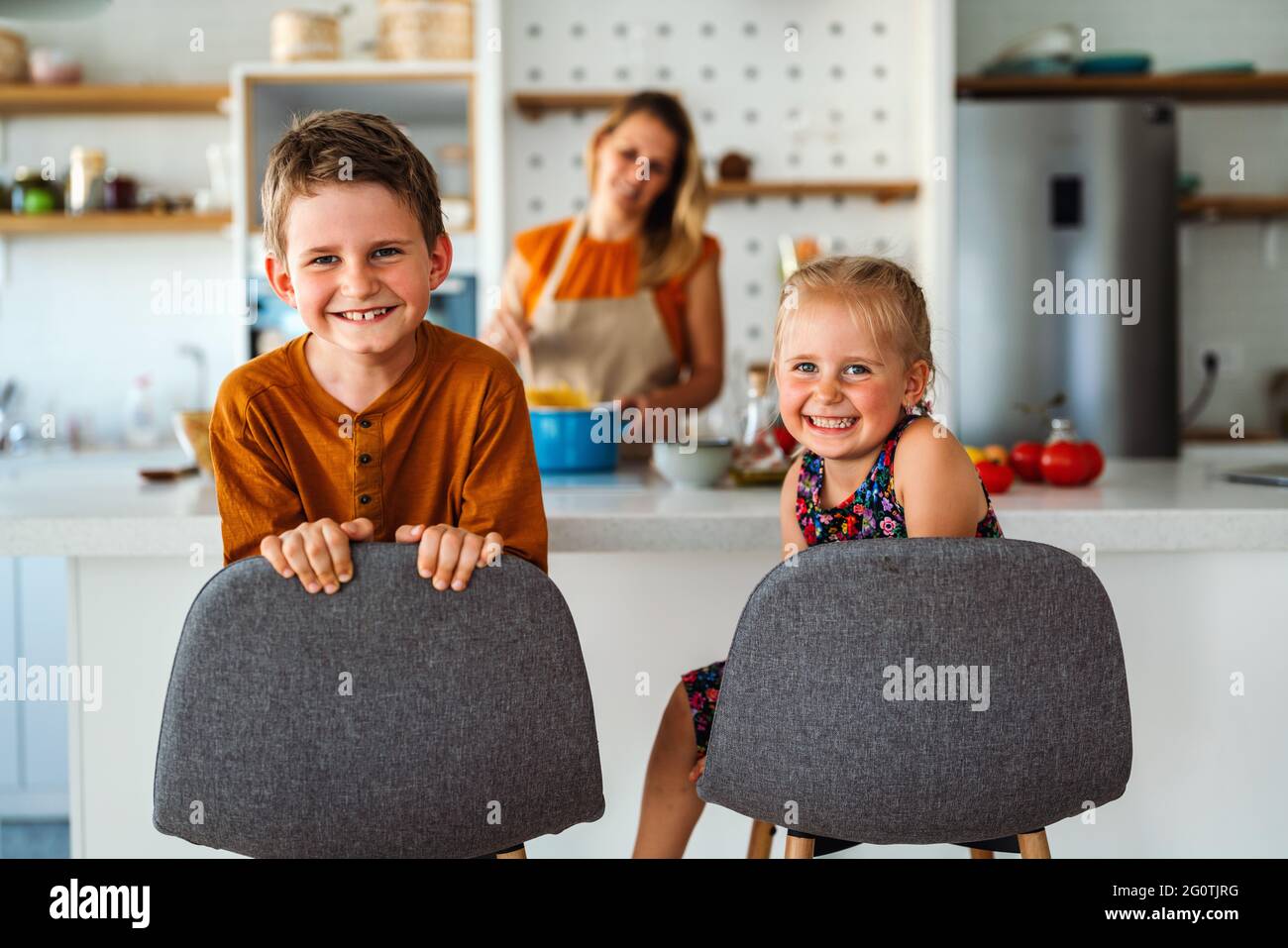 Famiglia felice a casa. Madre e bambini in cucina. Carino piccolo aiutante. Foto Stock