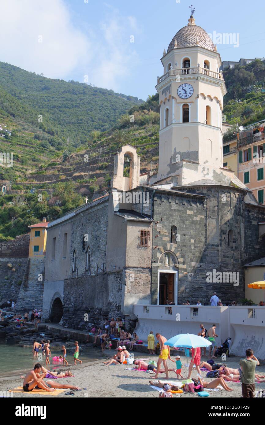 Persone che riposano in mare contro la Chiesa di Santa Margherita d'Antiochia a Vernazza, la Spezia, Liguria, Italia, Parco Nazionale delle cinque Terre Foto Stock