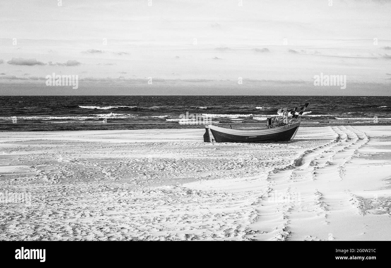 Barche da pesca sulla costa dell'Osstsee sulla spiaggia in Polonia in un aspetto malinconico bianco e nero. Spiaggia sul Mar Baltico con barche da pesca. Foto Stock