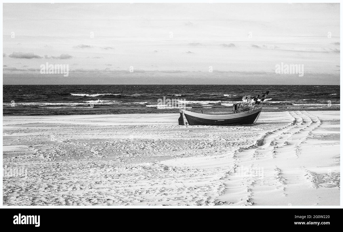 Barche da pesca sulla costa dell'Osstsee sulla spiaggia in Polonia in un aspetto malinconico bianco e nero. Spiaggia sul Mar Baltico con barche da pesca. Foto Stock