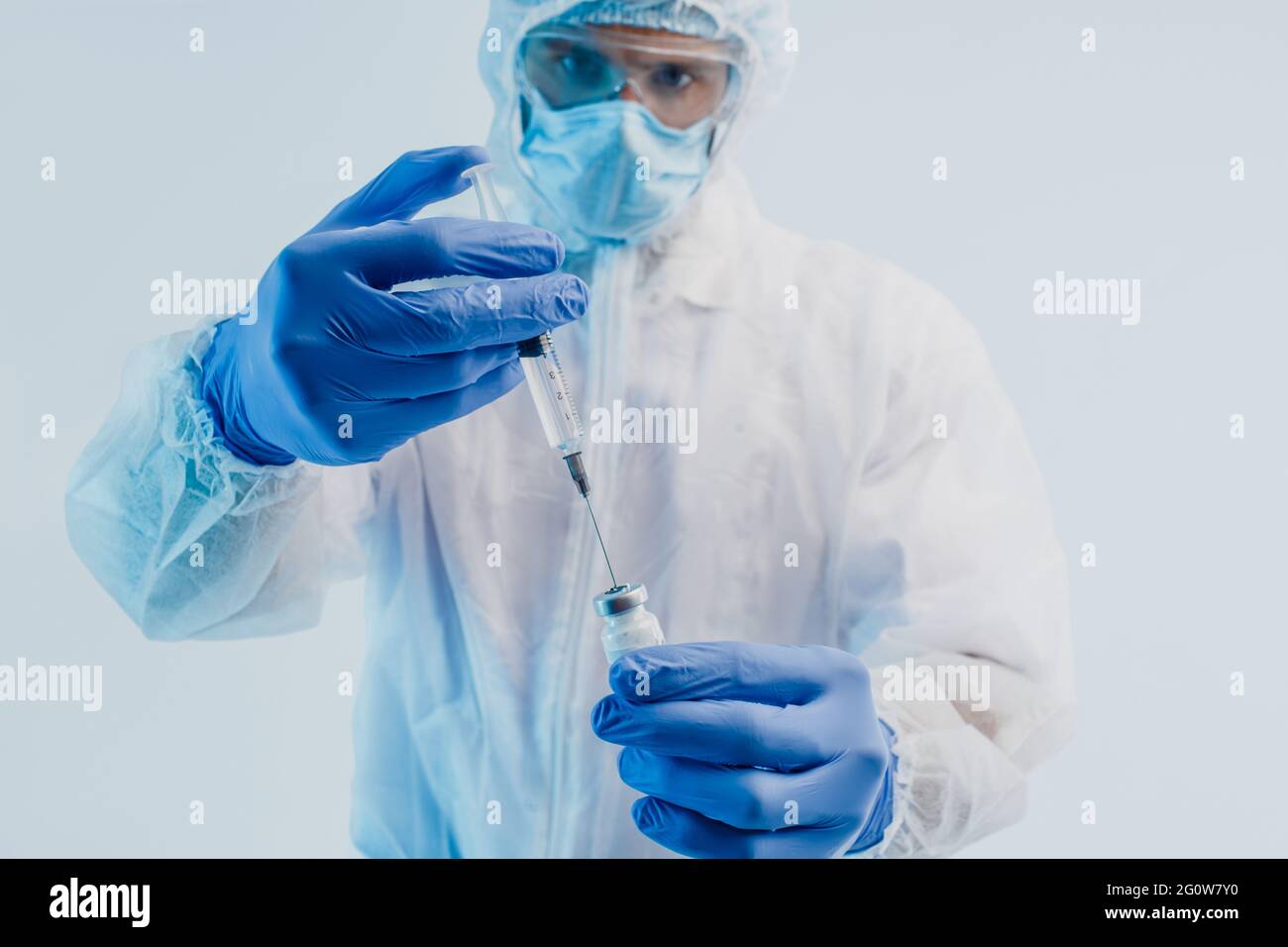 Il medico maschile versa il vaccino COVID-19 nella siringa Foto Stock