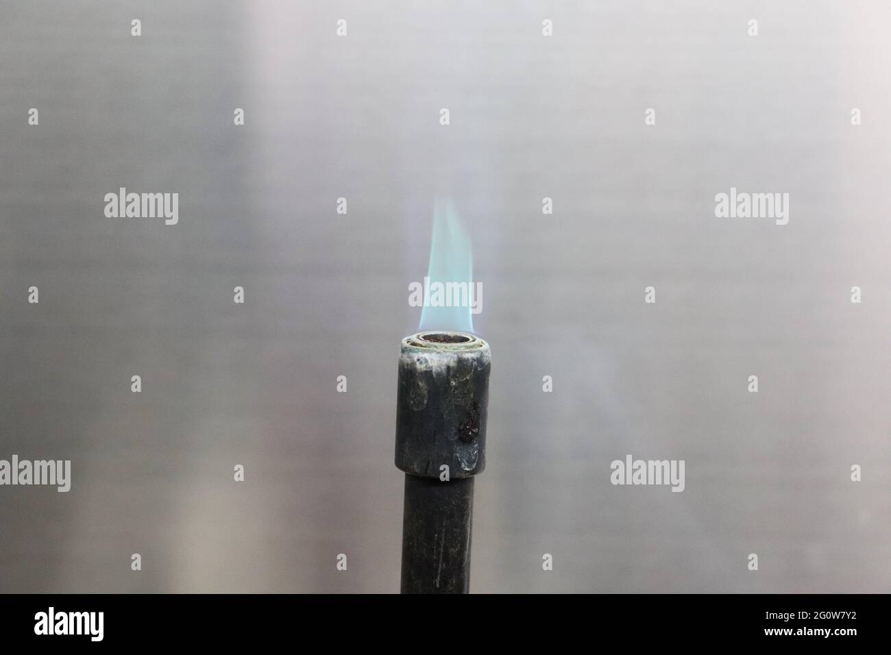 Un bruciatore Bunsen, chiamato dopo Robert Bunsen, è un tipo di bruciatore a gas utilizzato come apparecchiatura di laboratorio; produce una singola fiamma a gas aperta Foto Stock