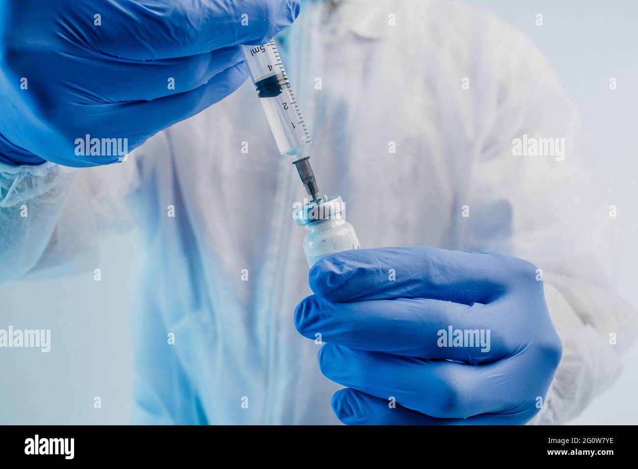 Il medico maschile versa il vaccino COVID-19 nella siringa Foto Stock