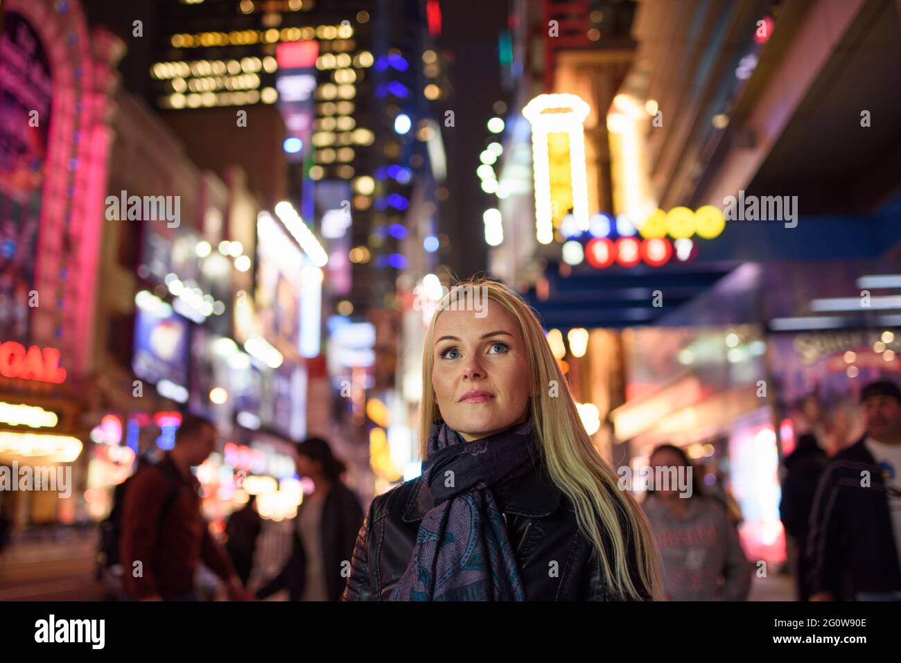 Donna adulta in una via della città illuminata di sera Foto Stock