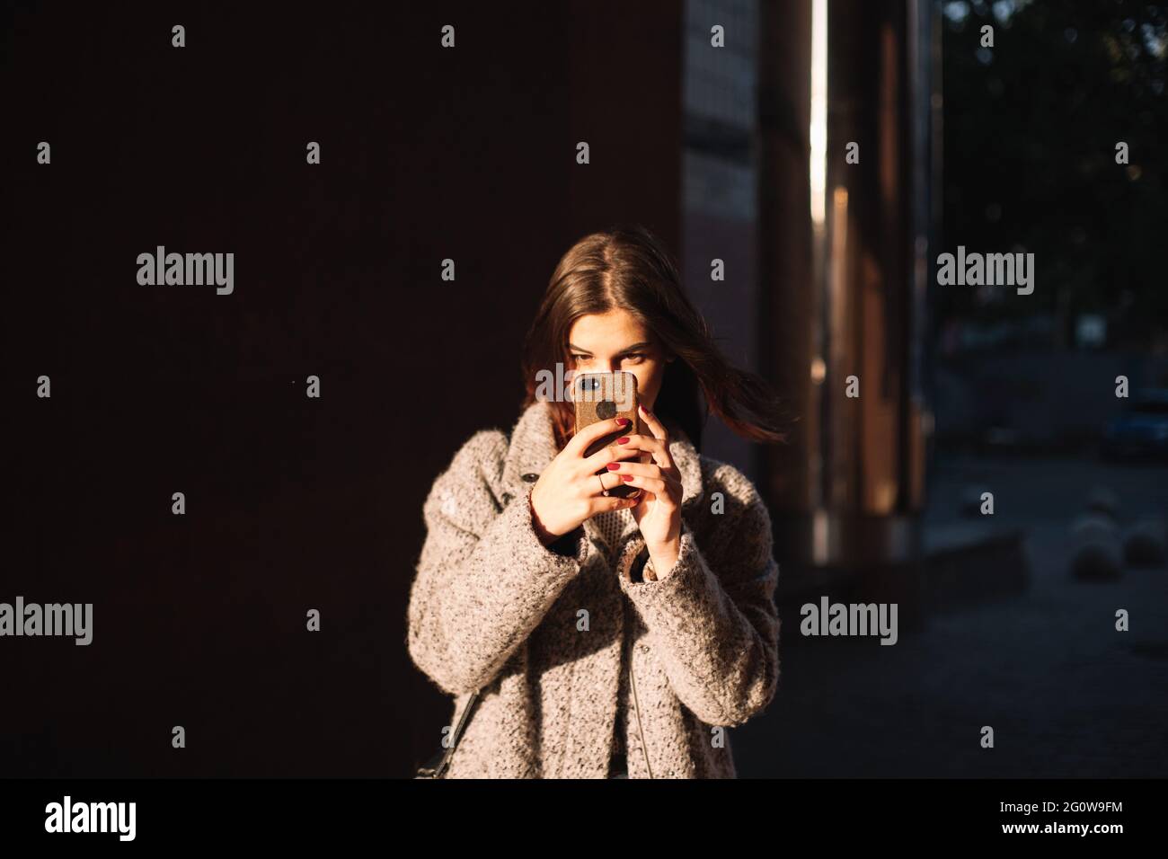 Giovane donna con smartphone in piedi in città Foto Stock