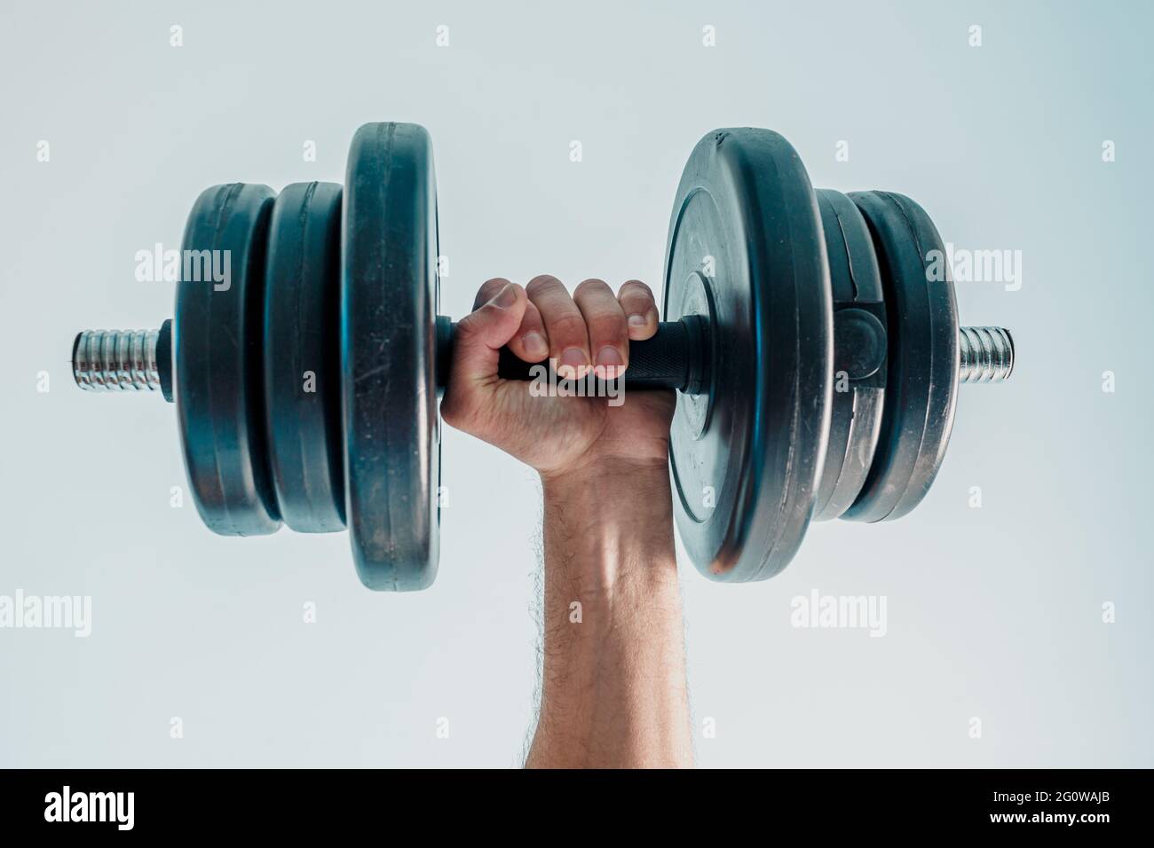 Primo piano di sportivo che tiene dumbell a mano Foto Stock