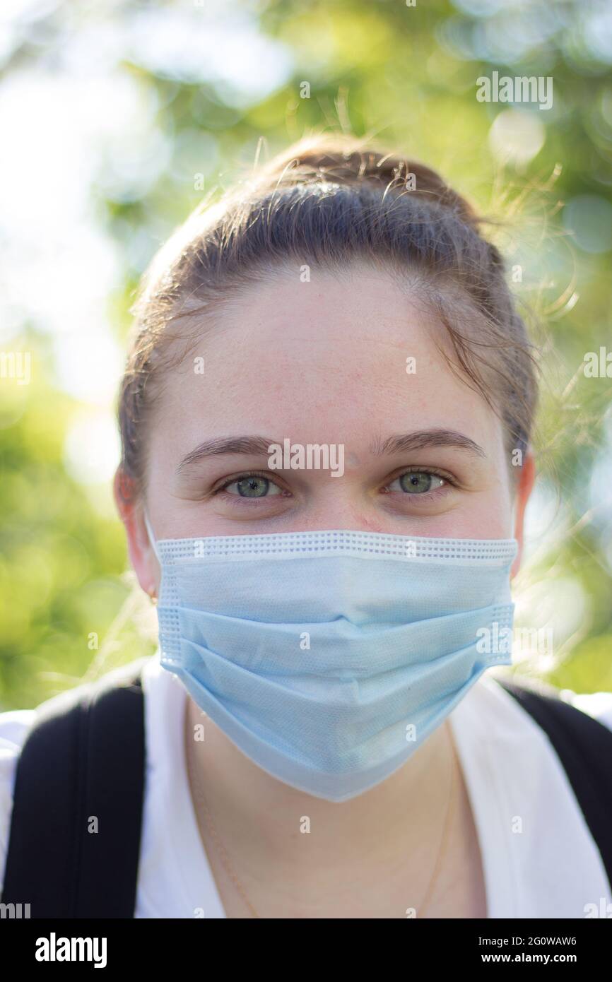 ragazza in una maschera in tempo soleggiato sulla strada Foto Stock