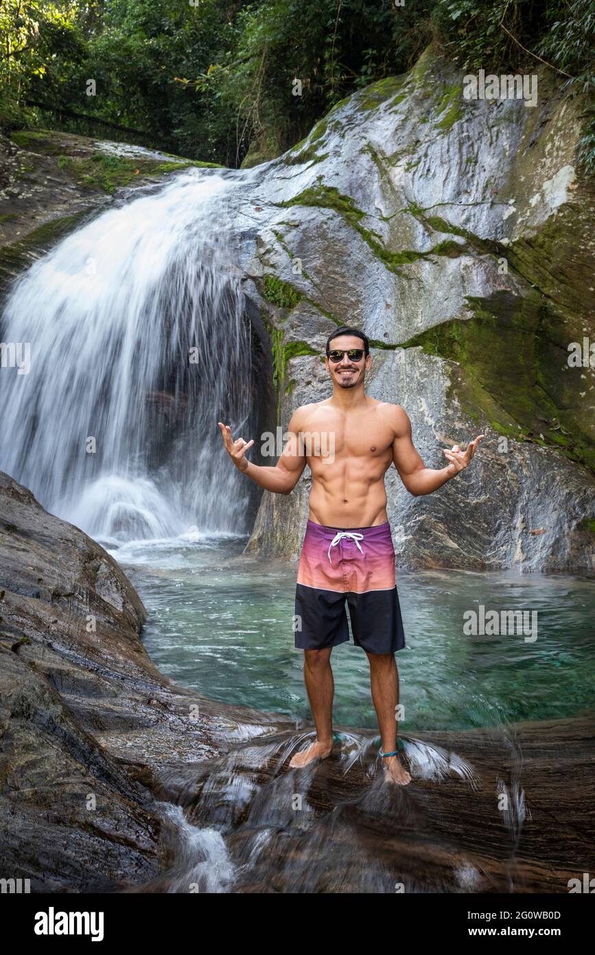 Uomo godendo bella cascata di acqua cristallina della foresta pluviale Foto Stock