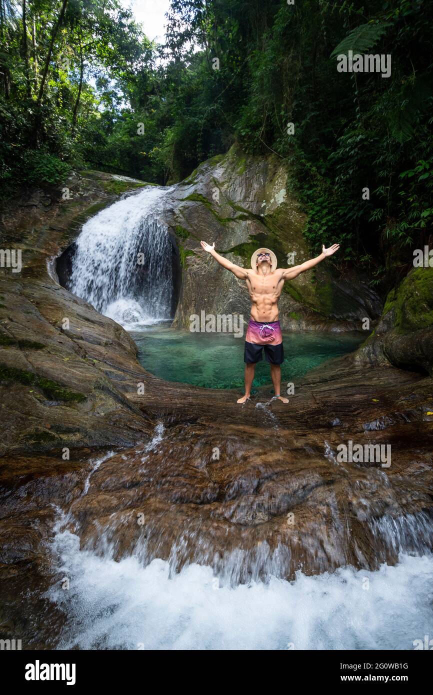 L'uomo gode di una bella piscina a cascata con acque cristalline della foresta pluviale Foto Stock