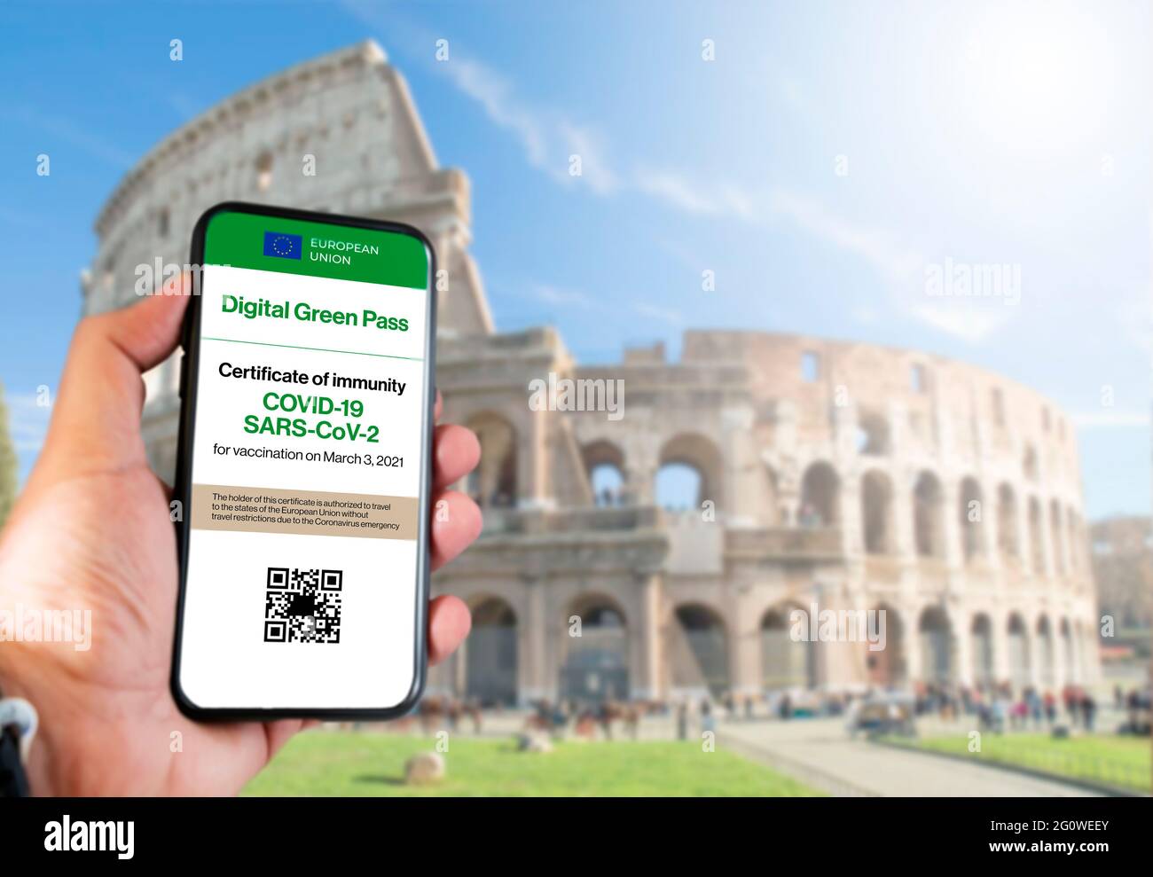Il pass verde digitale dell'Unione europea con il codice QR sullo schermo di un cellulare tenuto da una mano con il colosseo sfocato sullo sfondo. Immun Foto Stock