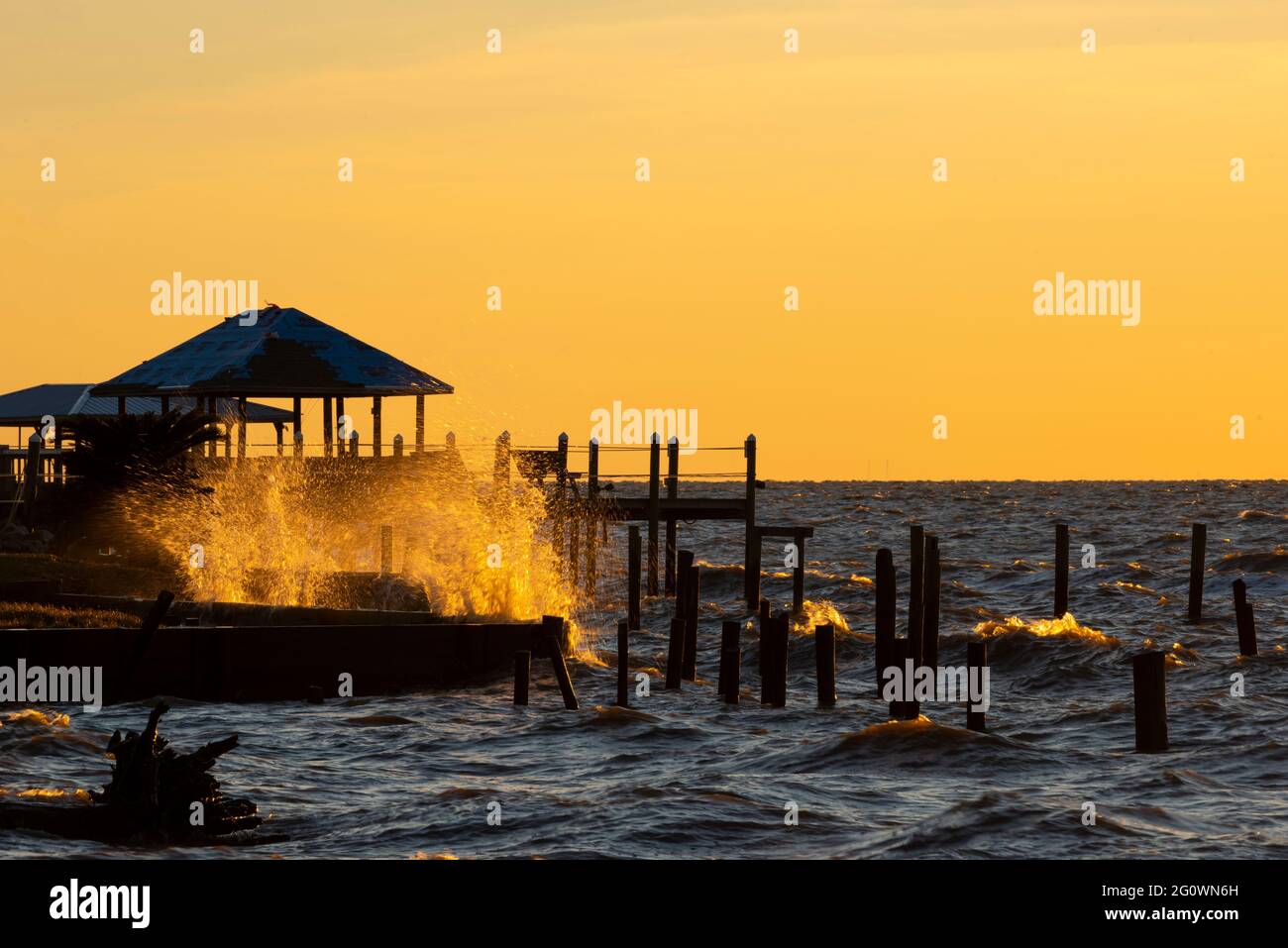 Le onde si infrangono contro un molo a Fairhope, Alabama, USA, al tramonto il 29 ottobre 2020. Foto Stock