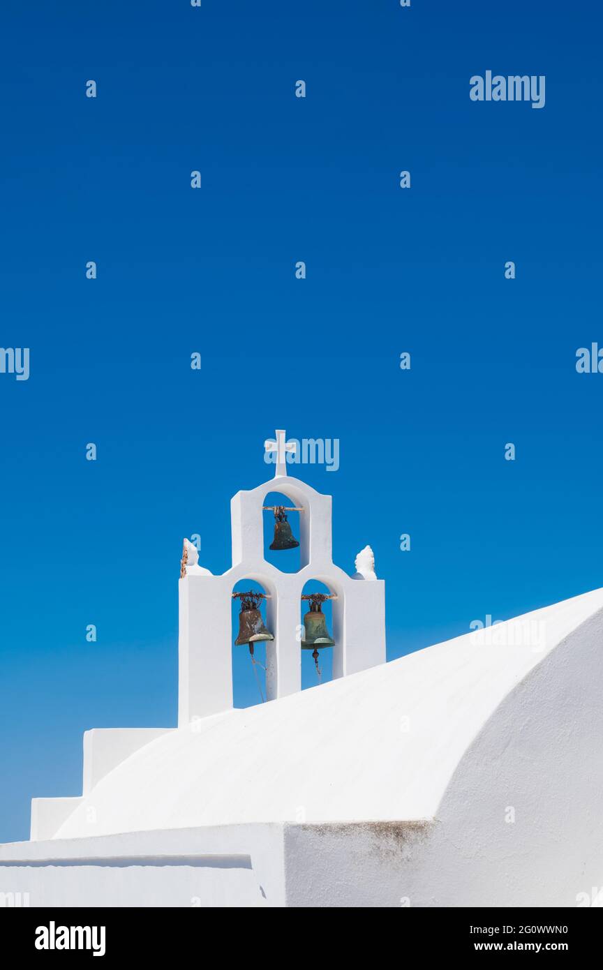 Il campanile bianco della tradizionale chiesa greco-ortodossa sull'isola di Santorini. Cielo blu su sfondo. Foto Stock