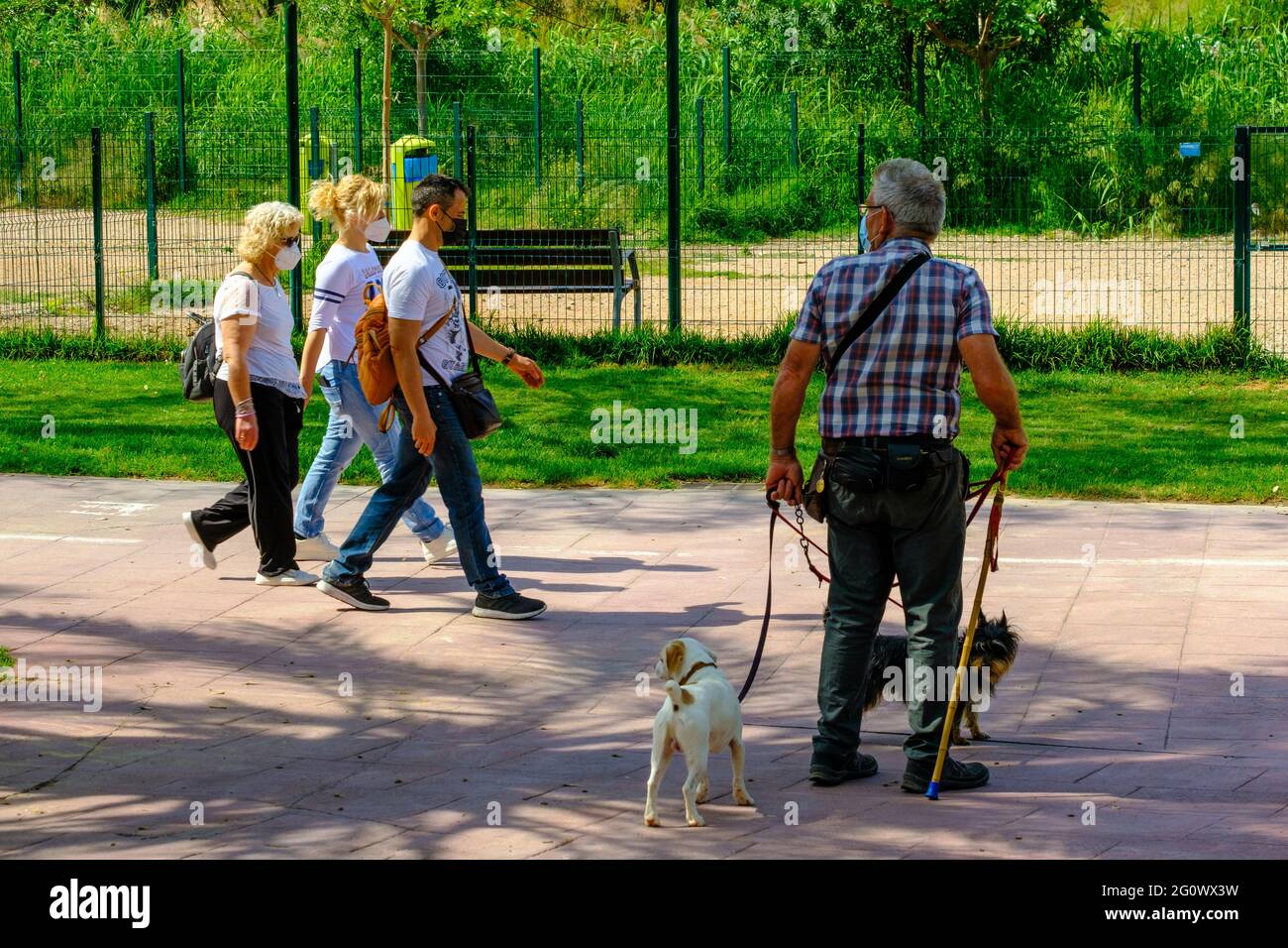 VALENCIA, SPAGNA - 25 maggio 2021: Alcune persone camminano intorno con le maschere, mentre una persona anziana le guarda. Foto Stock