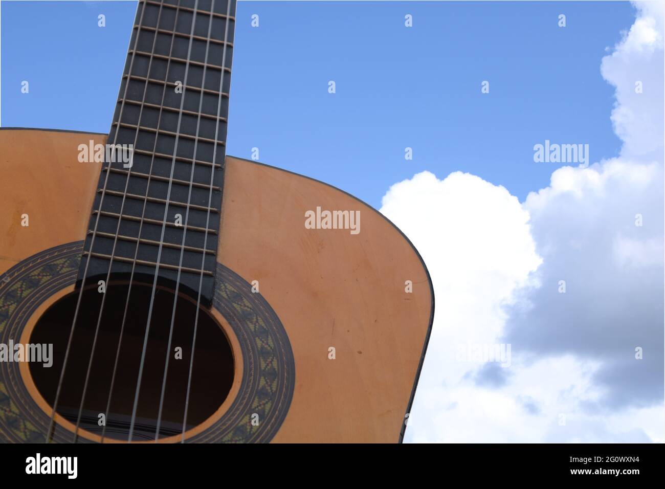 Chitarra in legno con cielo blu e nuvole sullo sfondo con spazio copia. Concetto di musica celeste Foto Stock