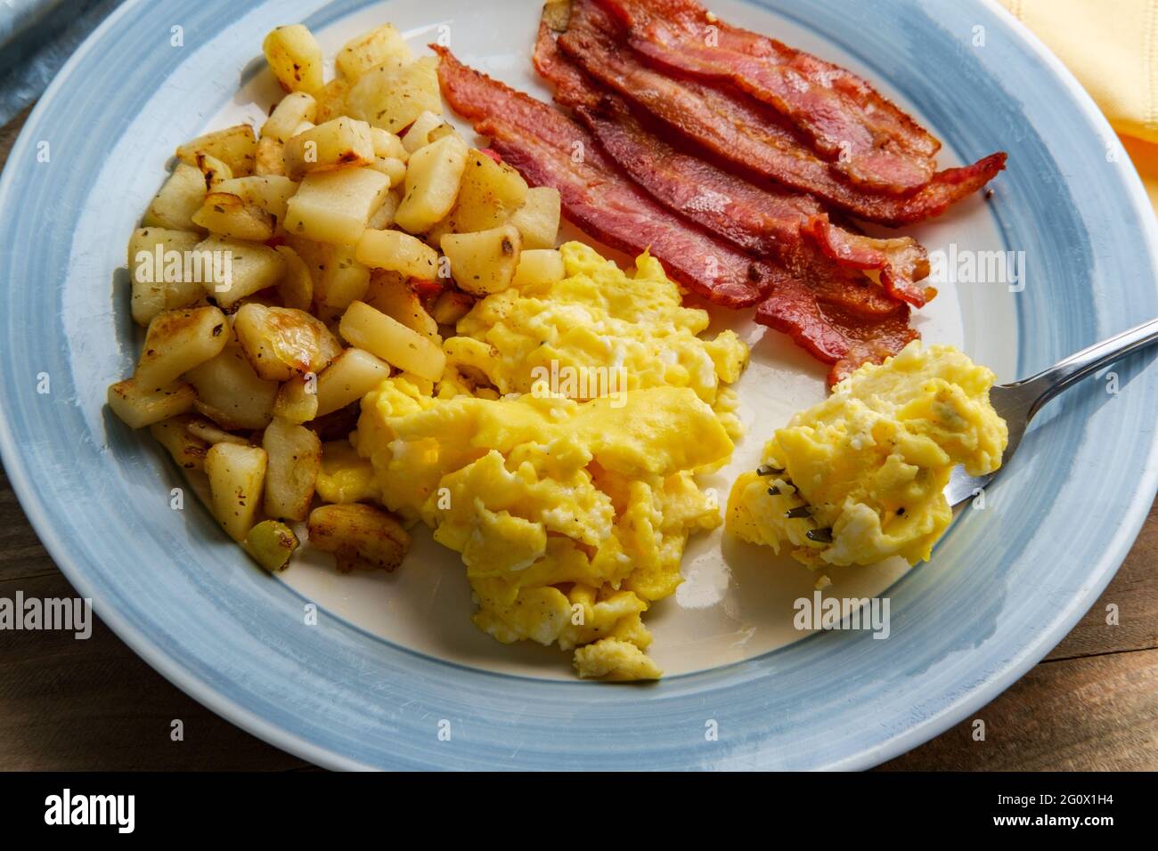La colazione all'americana comprende uova strapazzate con patatine fritte e  pancetta croccante Foto stock - Alamy