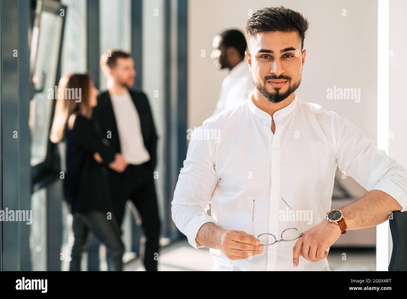 Ritratto di bell'uomo d'affari in ufficio e dei suoi colleghi sullo sfondo Foto Stock
