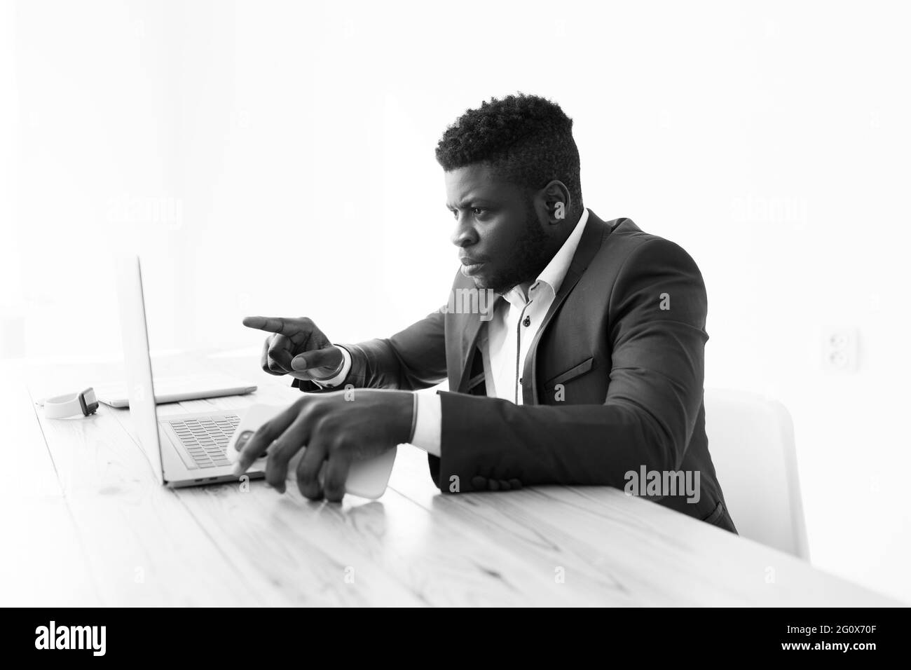 Ritratto in bianco e nero freelance afro-americano sedersi alla scrivania dell'ufficio usando il laptop leggere e-mail, tenere riunioni online, fare lavoro online da casa Foto Stock